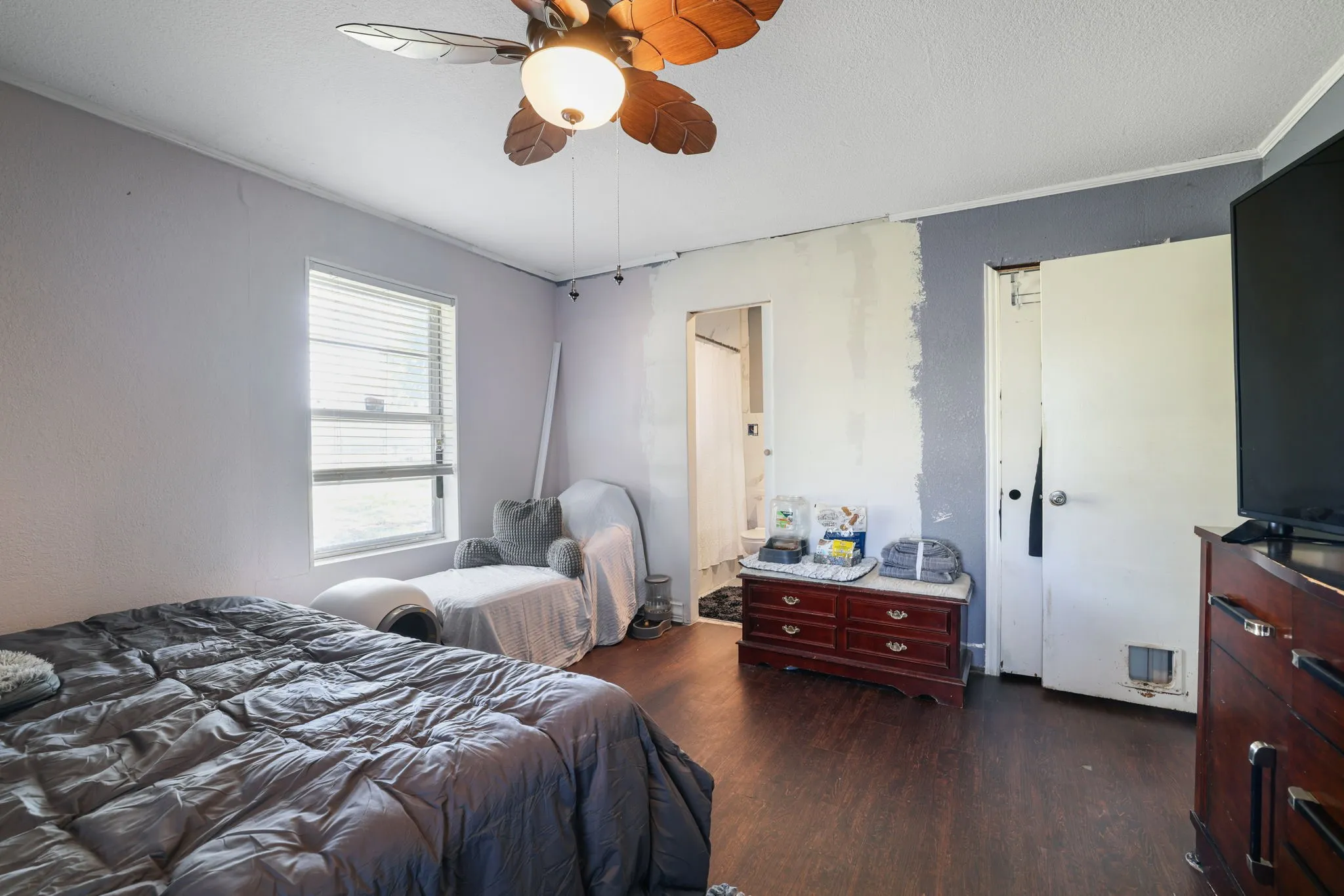 Wood-finish flooring, ceiling fan with light fixture, and a window with horizontal blinds