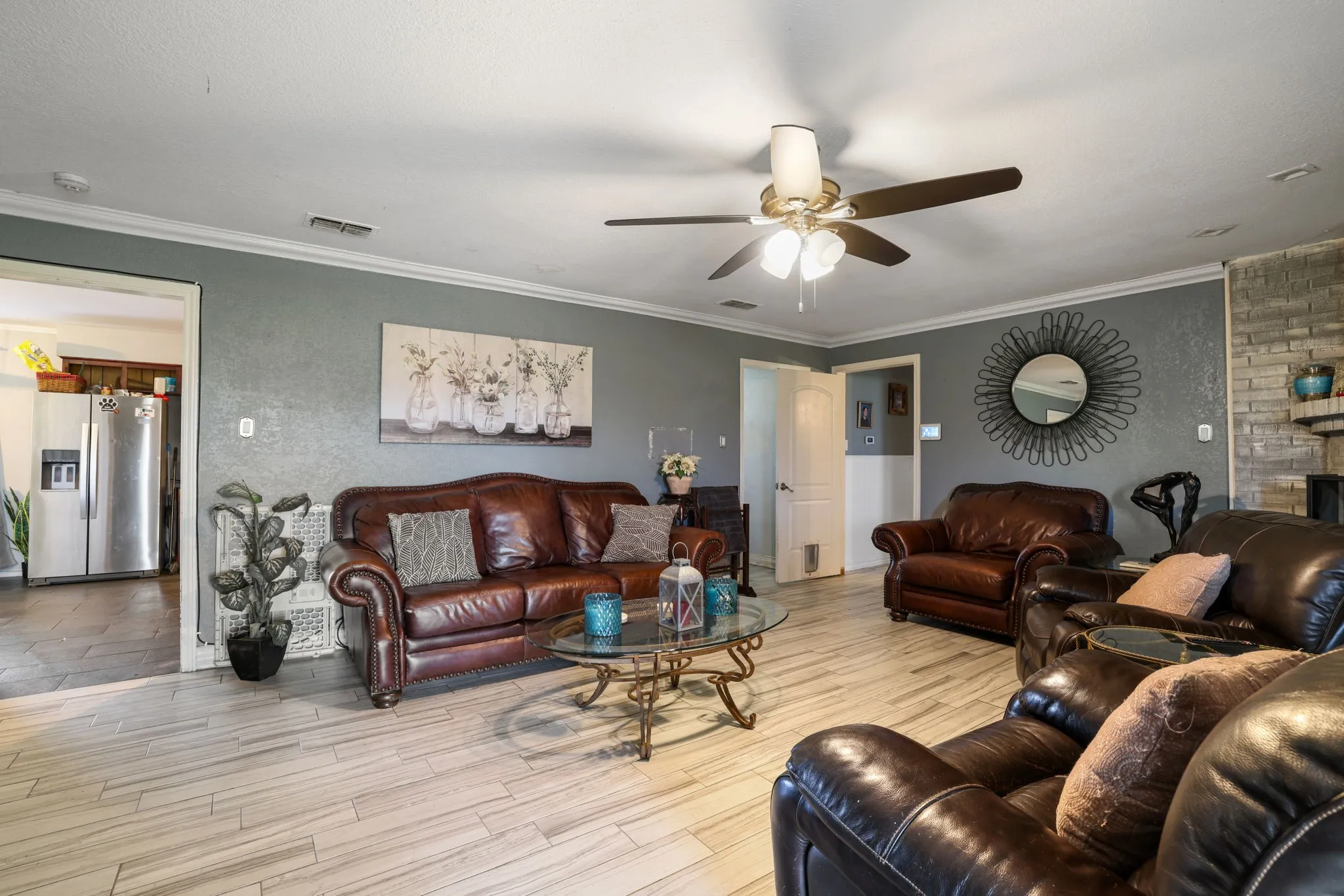 Living area with wood-finish flooring, crown molding, and a ceiling fan