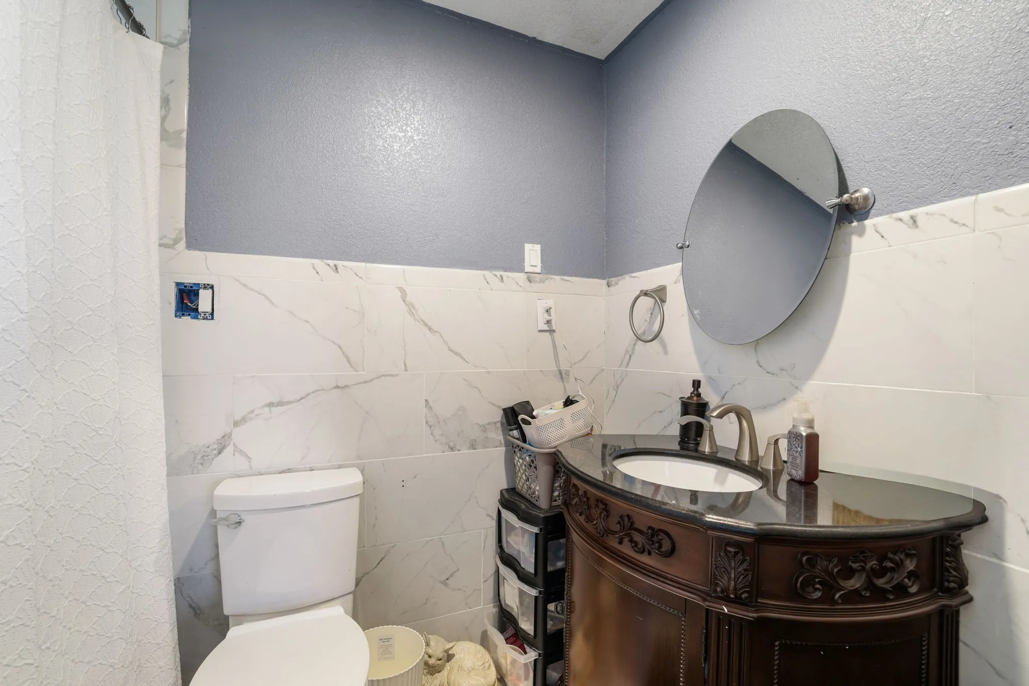 Curved vanity with an undermount sink, dark countertop, and brushed nickel faucet