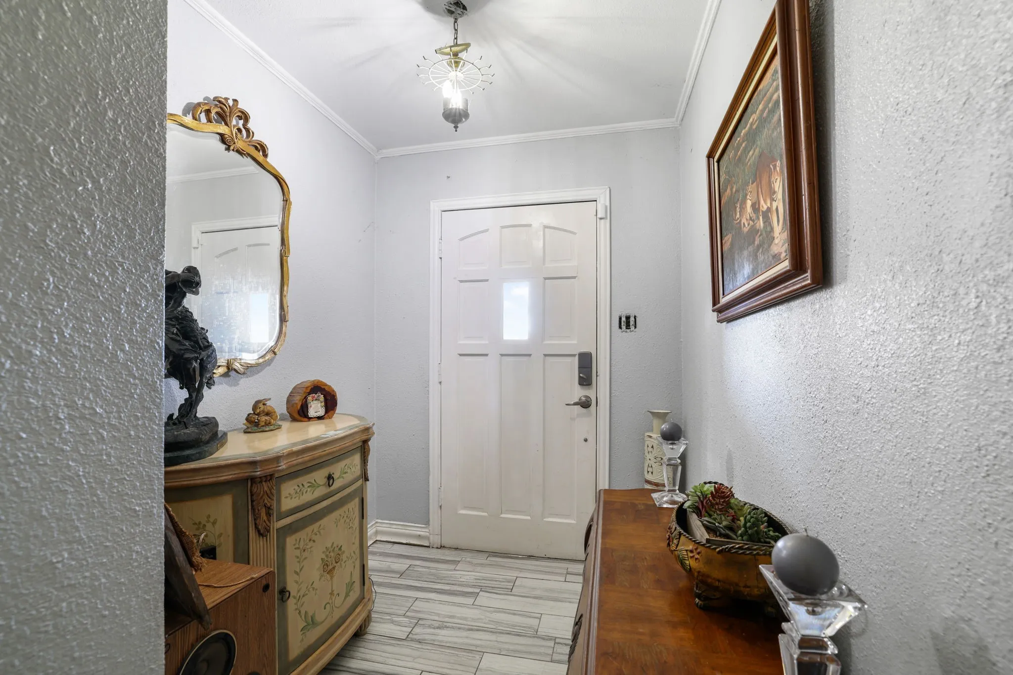 Wood-finish flooring with crown molding and a paneled entry door