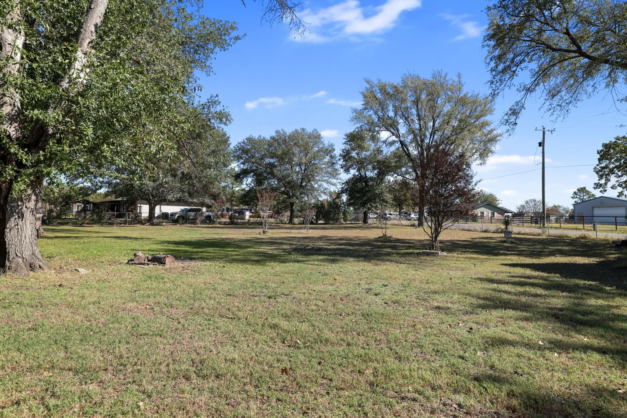 Expansive grassy yard with mature trees and a clear sky backdrop