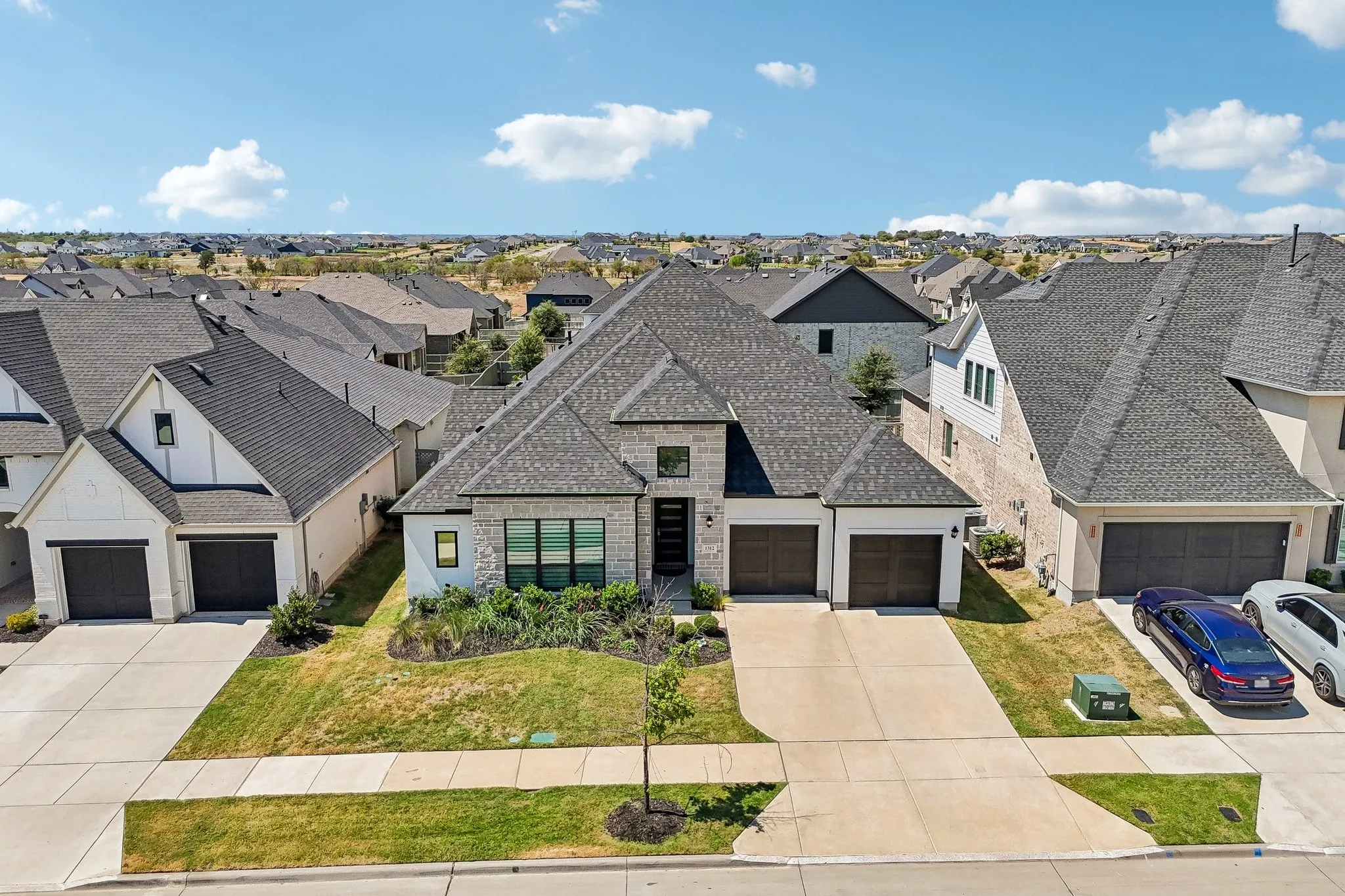 Exterior featuring a stone and brick facade, dark shingle roof, attached two-car garage, and a concrete driveway