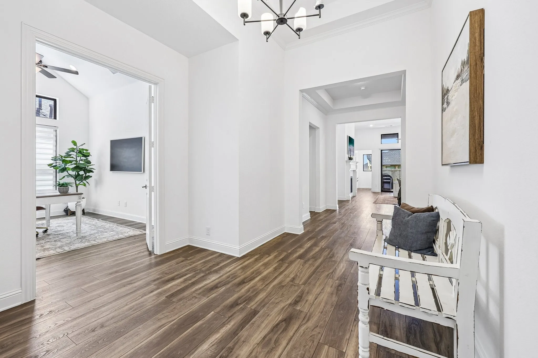 Hallway featuring wood-finish flooring, high ceilings, a contemporary chandelier, and recessed lighting
