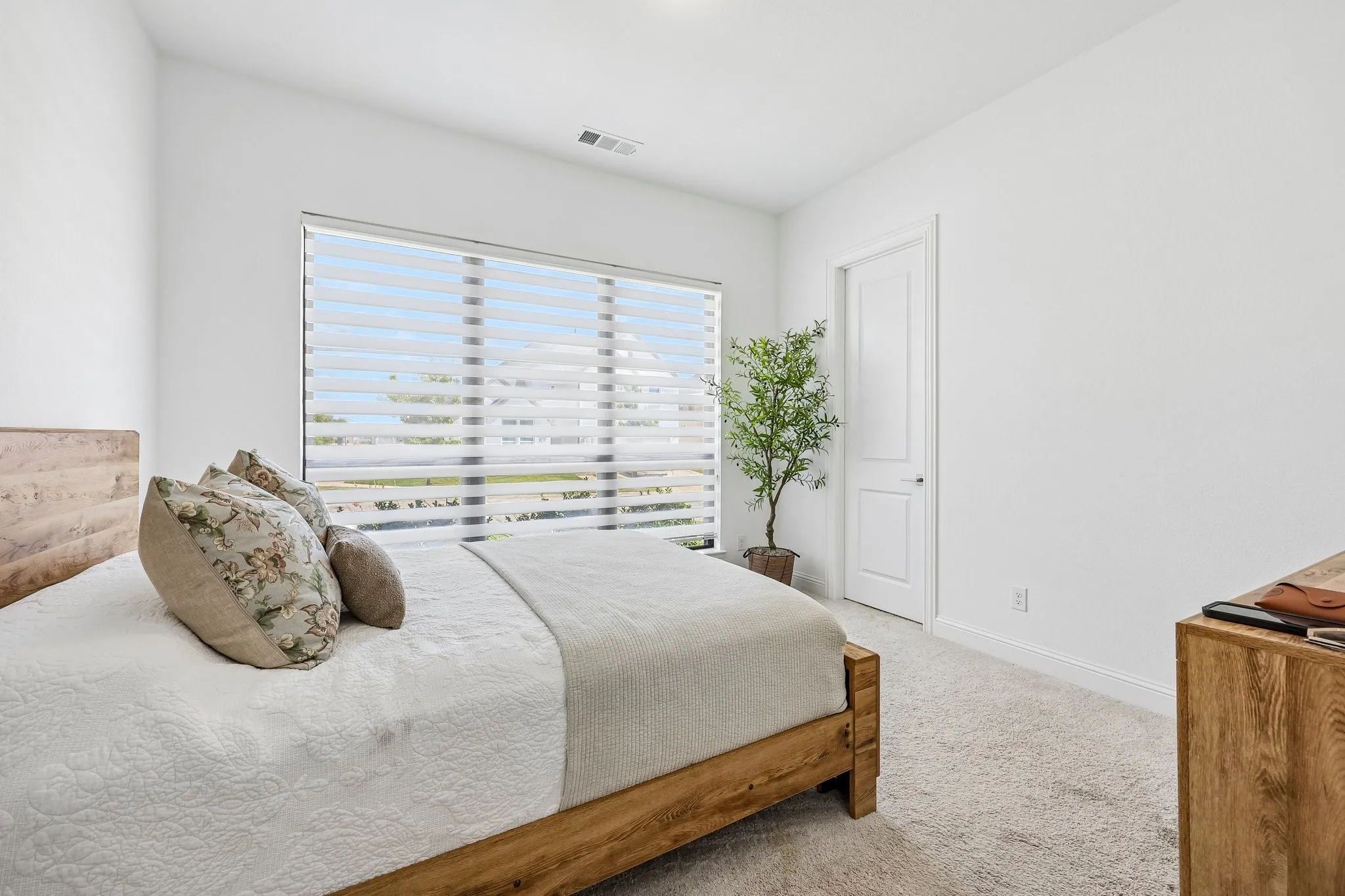 Large window with horizontal blinds, light-toned carpet flooring, white walls, and a paneled white door