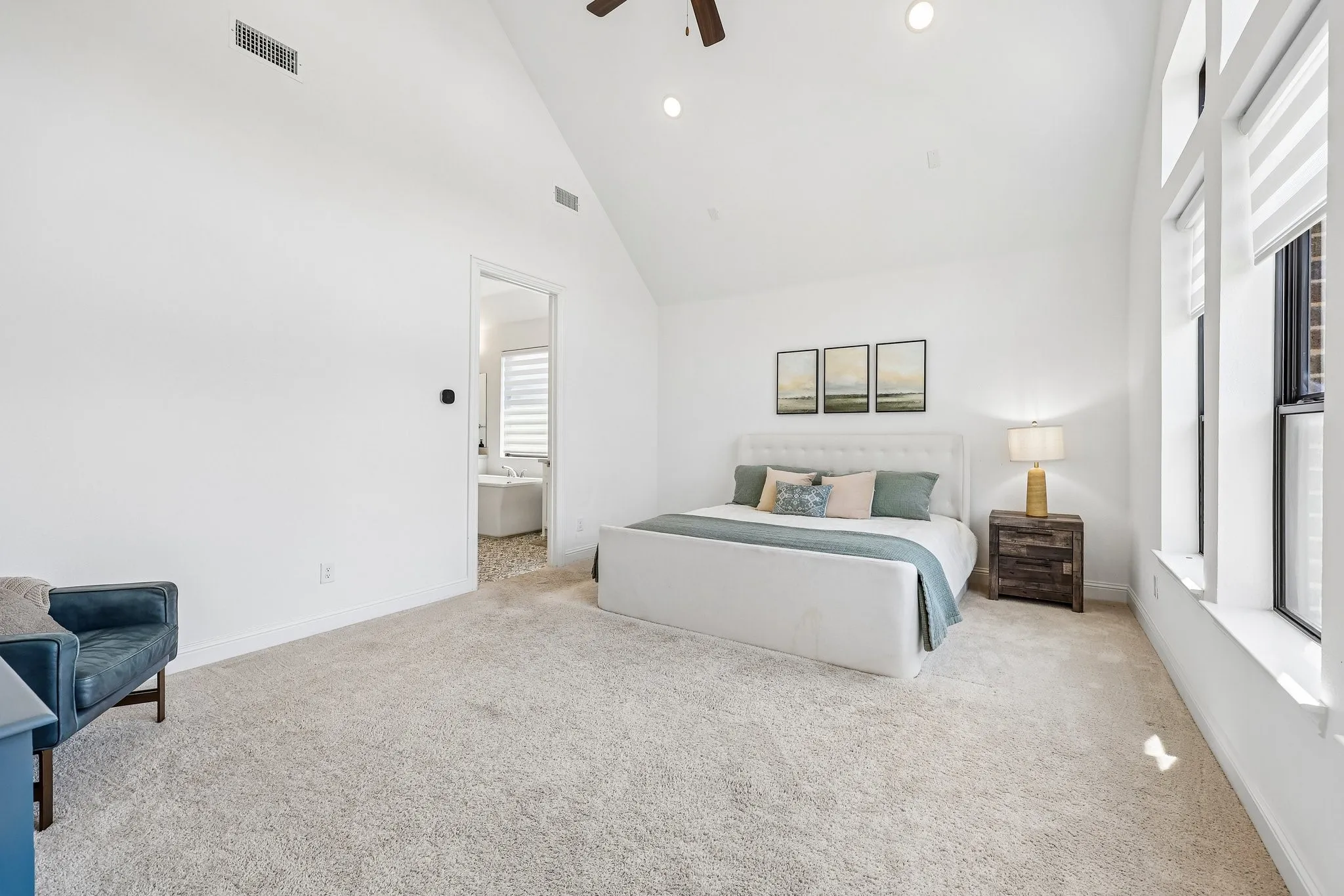 Vaulted ceiling with recessed lighting, large windows with blinds, carpeted flooring, and an open doorway