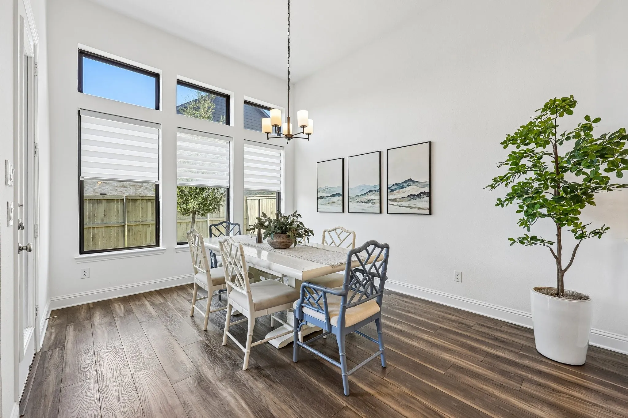 Wood-finish flooring, high ceilings, multiple large windows with integrated blinds, and a built-in chandelier