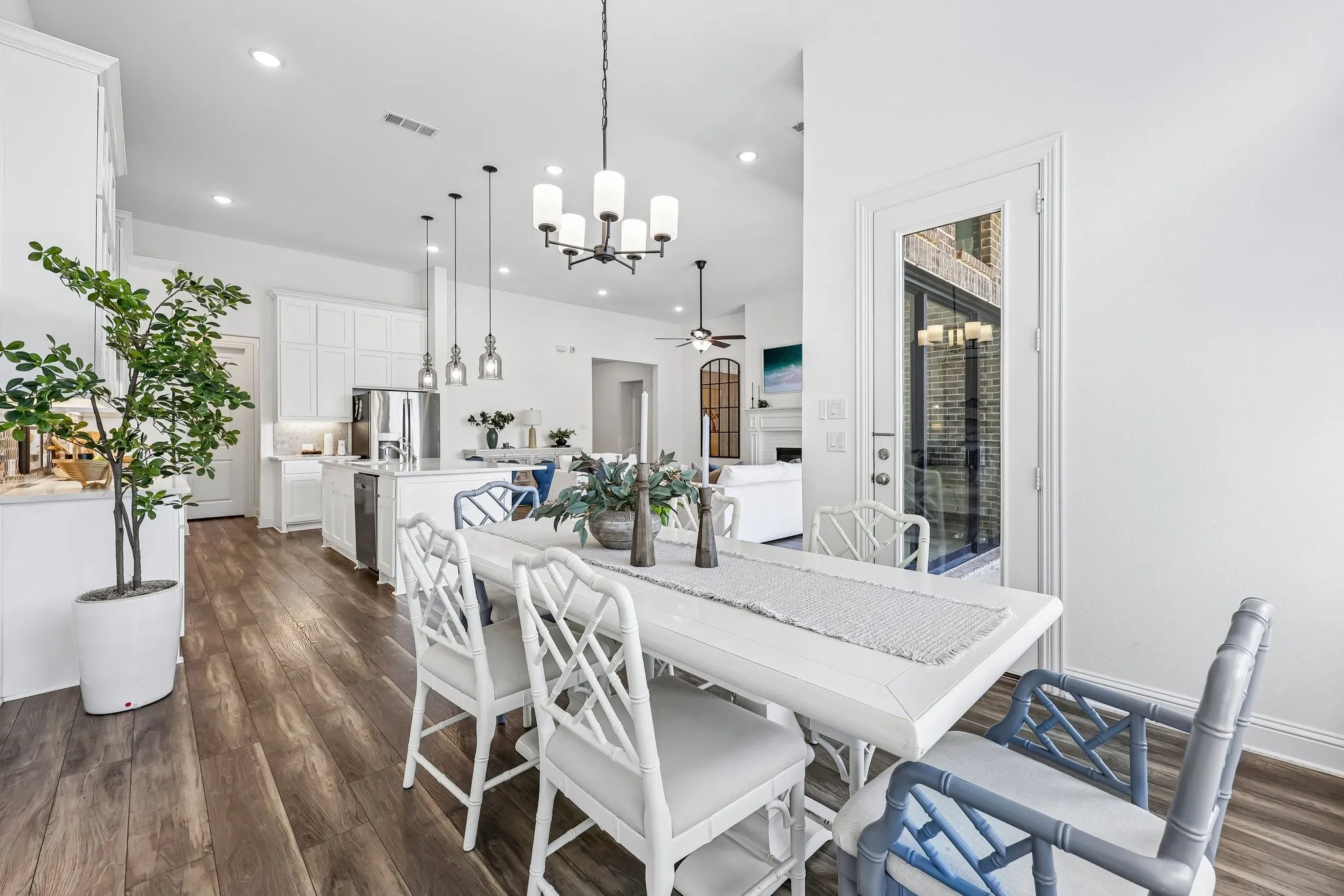 Open-concept living space featuring wood-finish flooring, white cabinetry, recessed lighting, and a glass-paneled exterior door