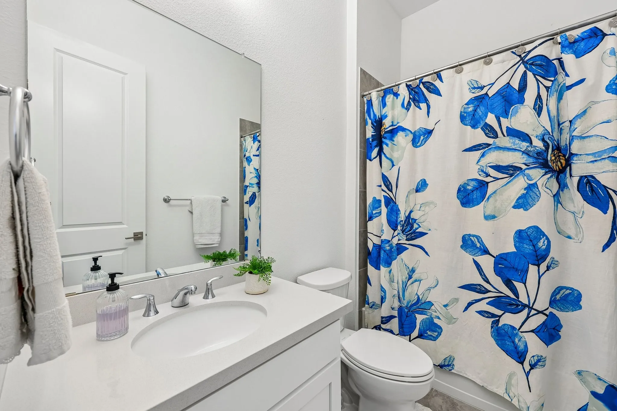 White vanity with a single basin sink, chrome faucet, and expansive wall-mounted mirror