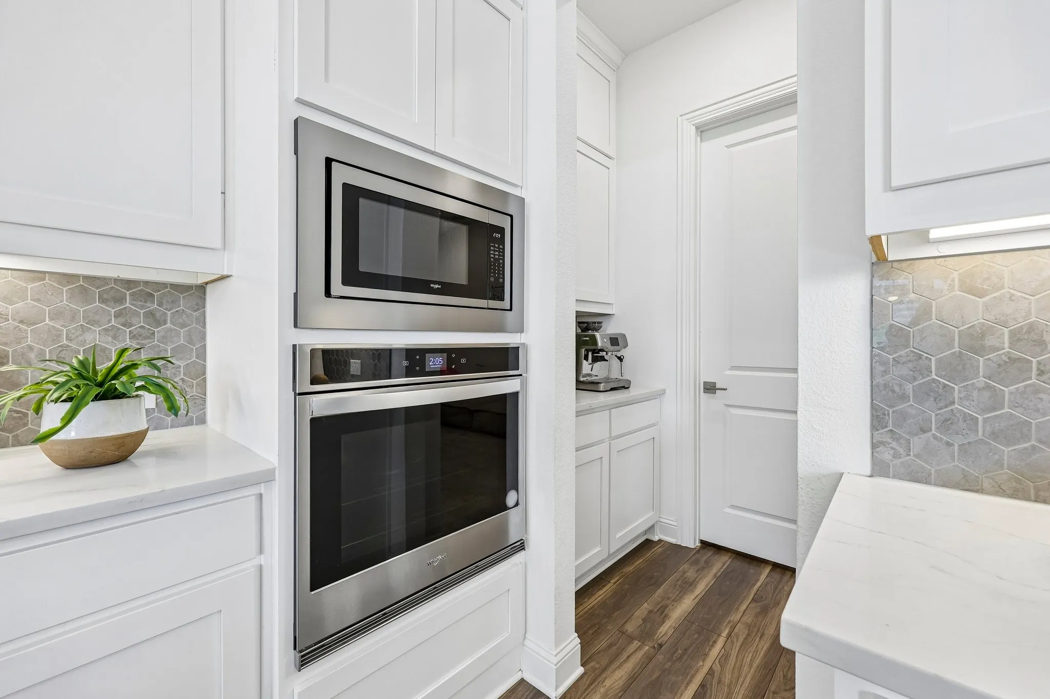 White shaker-style cabinetry with built-in stainless steel microwave and oven