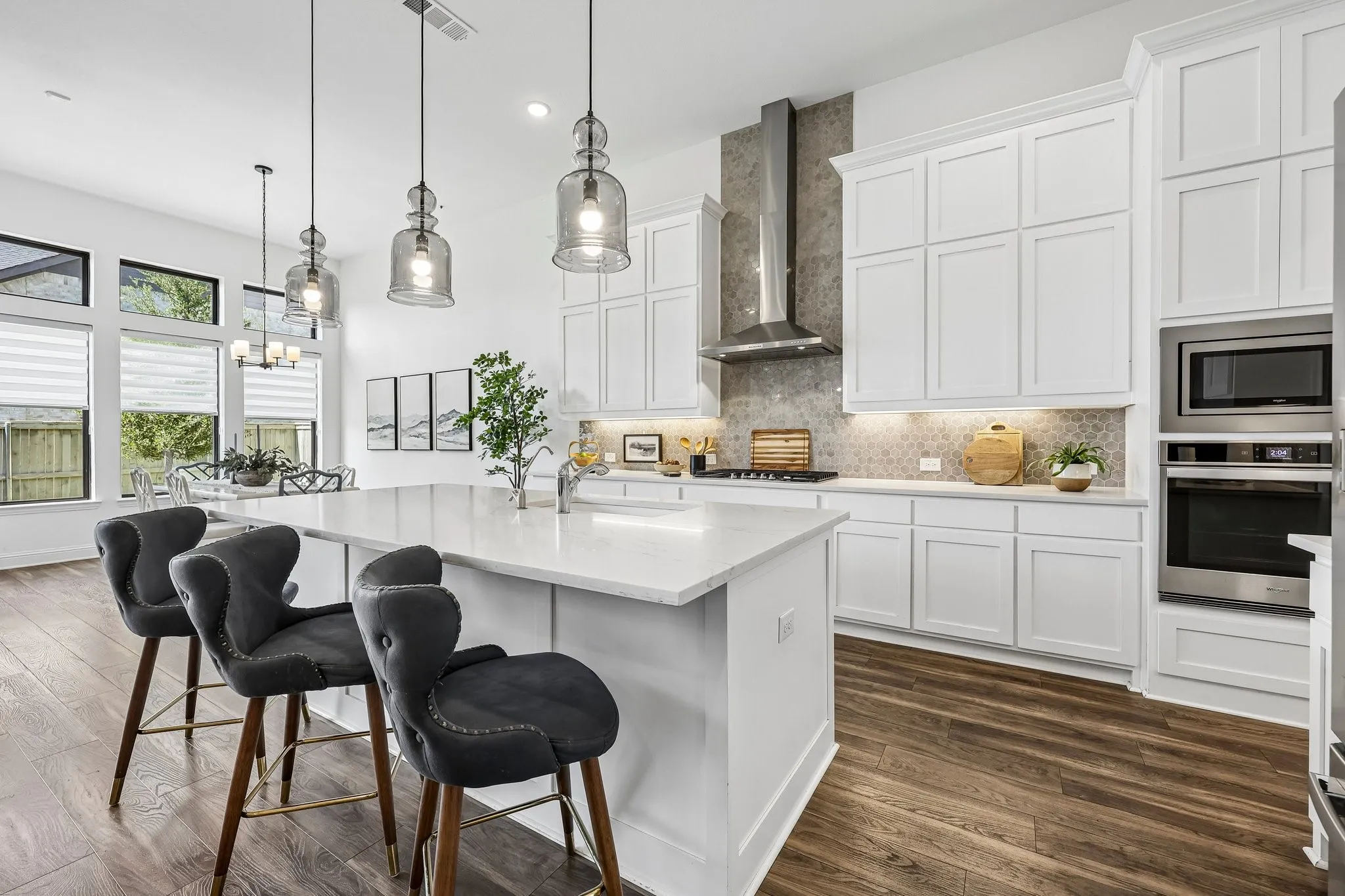 Kitchen featuring an expansive center island, integrated stainless steel appliances, upper and lower cabinetry, and wood-finish flooring