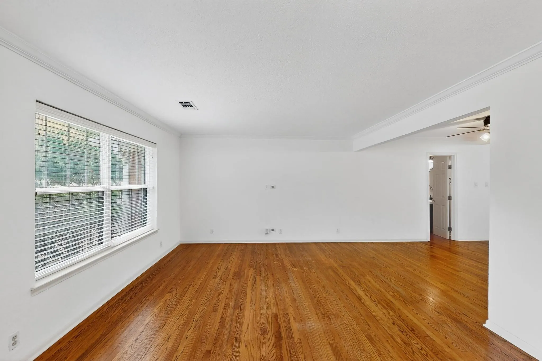 Empty room with ornamental molding, wood finished floors, and ceiling fan