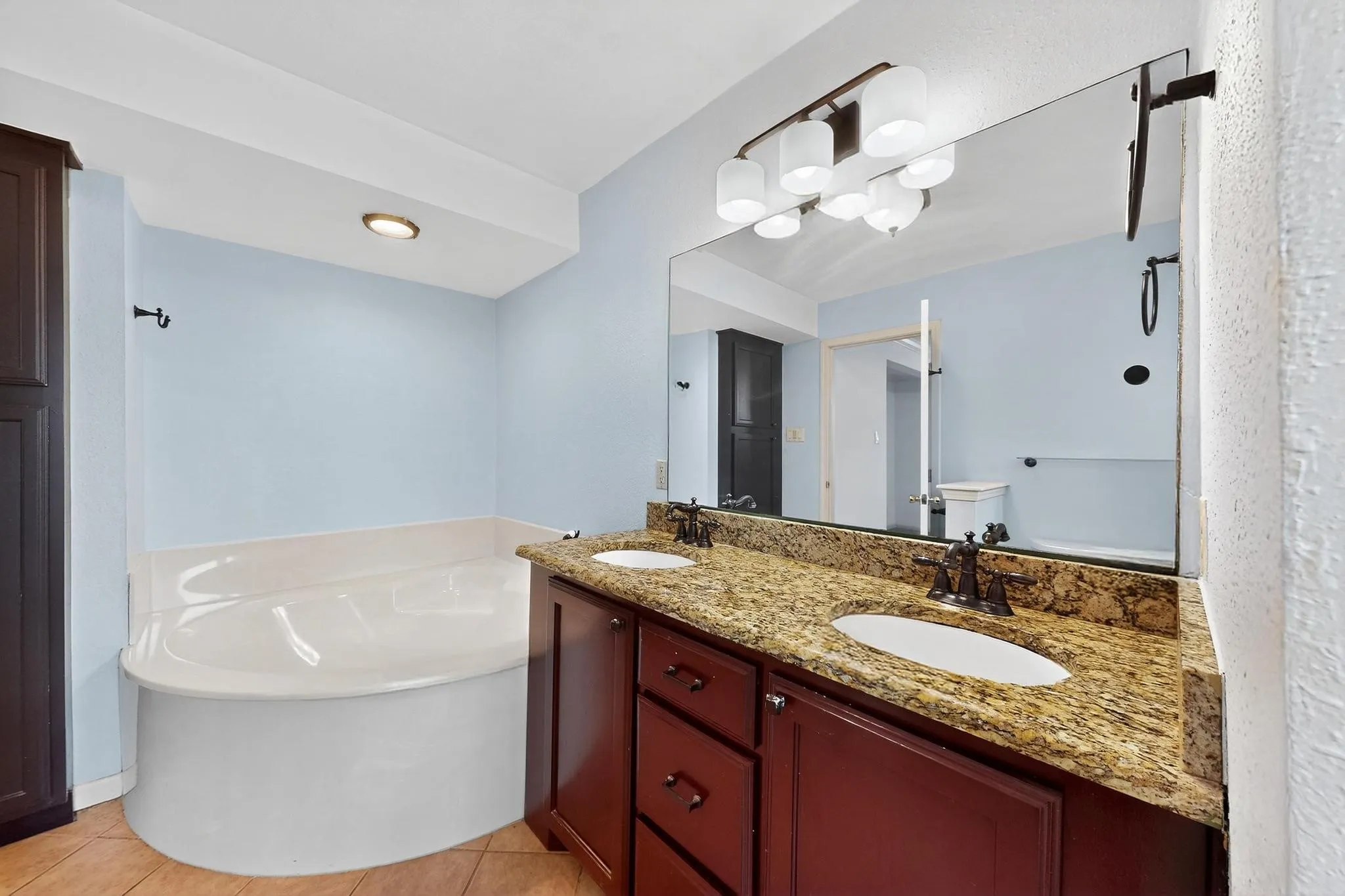 Full bathroom with a bath, double vanity, and tile patterned floors