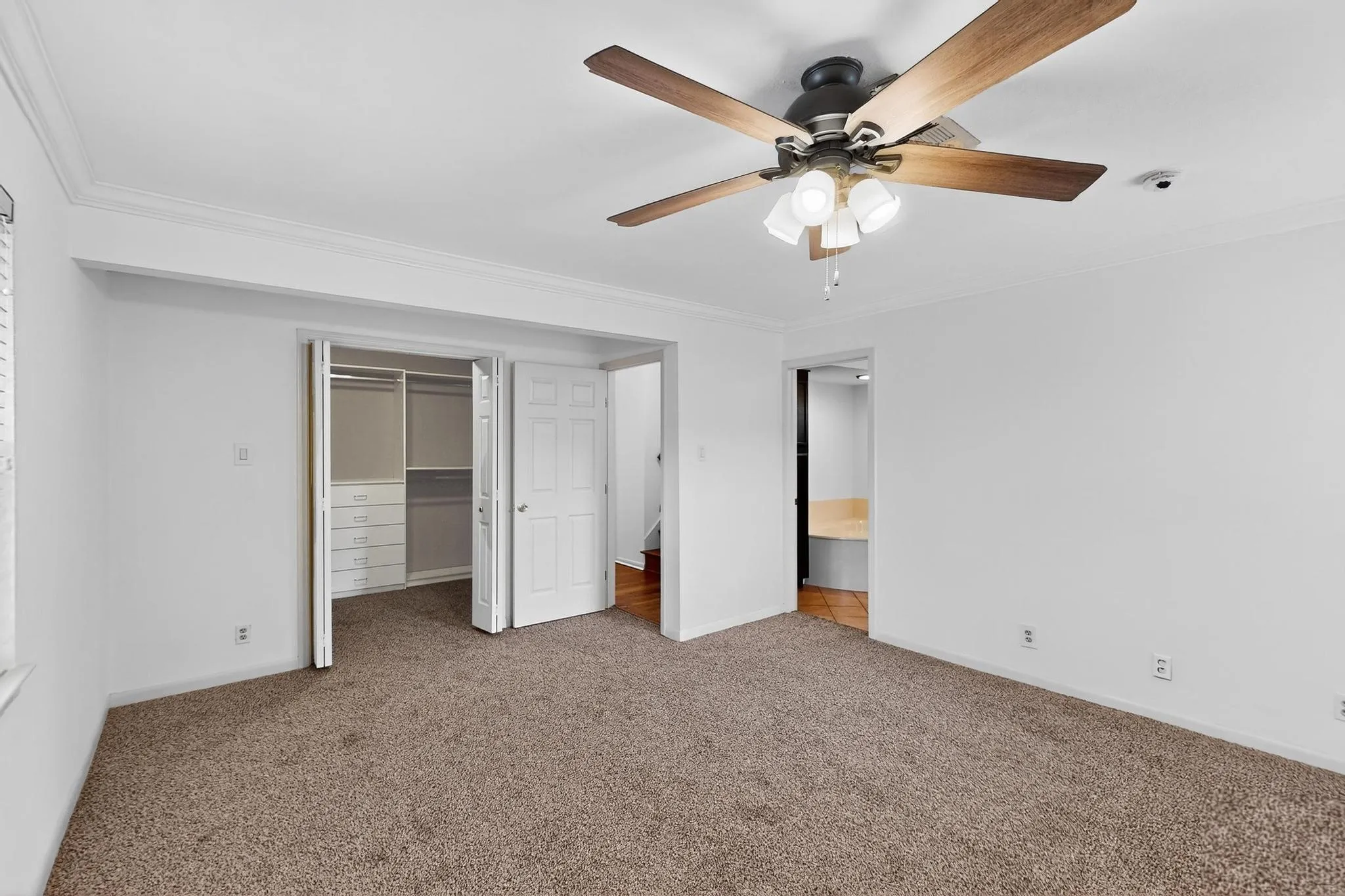 Unfurnished bedroom featuring carpet, crown molding, a closet, and ceiling fan