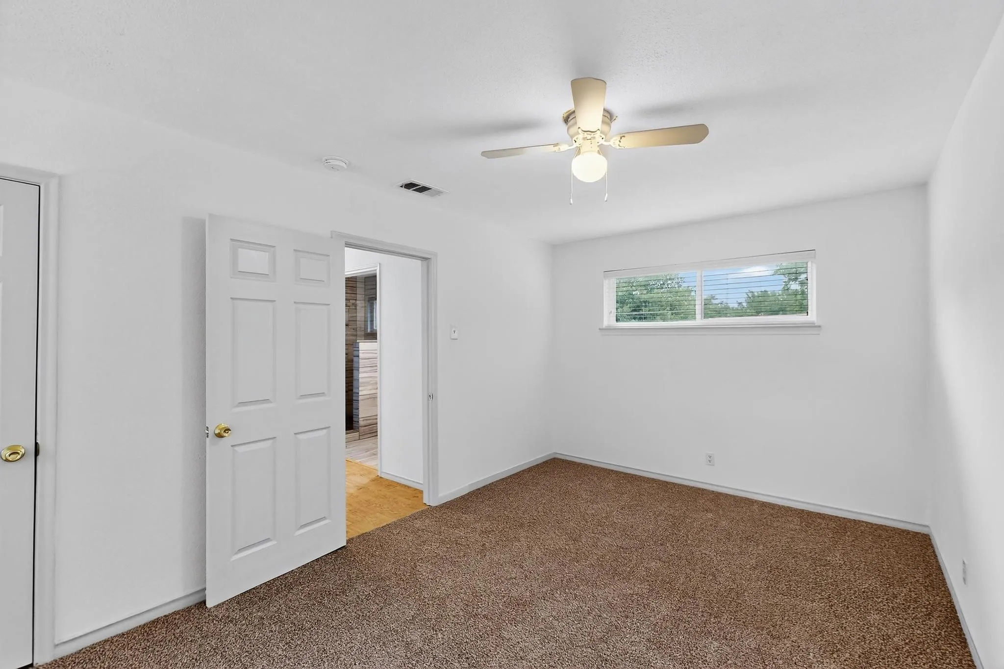 Spare room featuring light colored carpet, ceiling fan, and a smoke detector