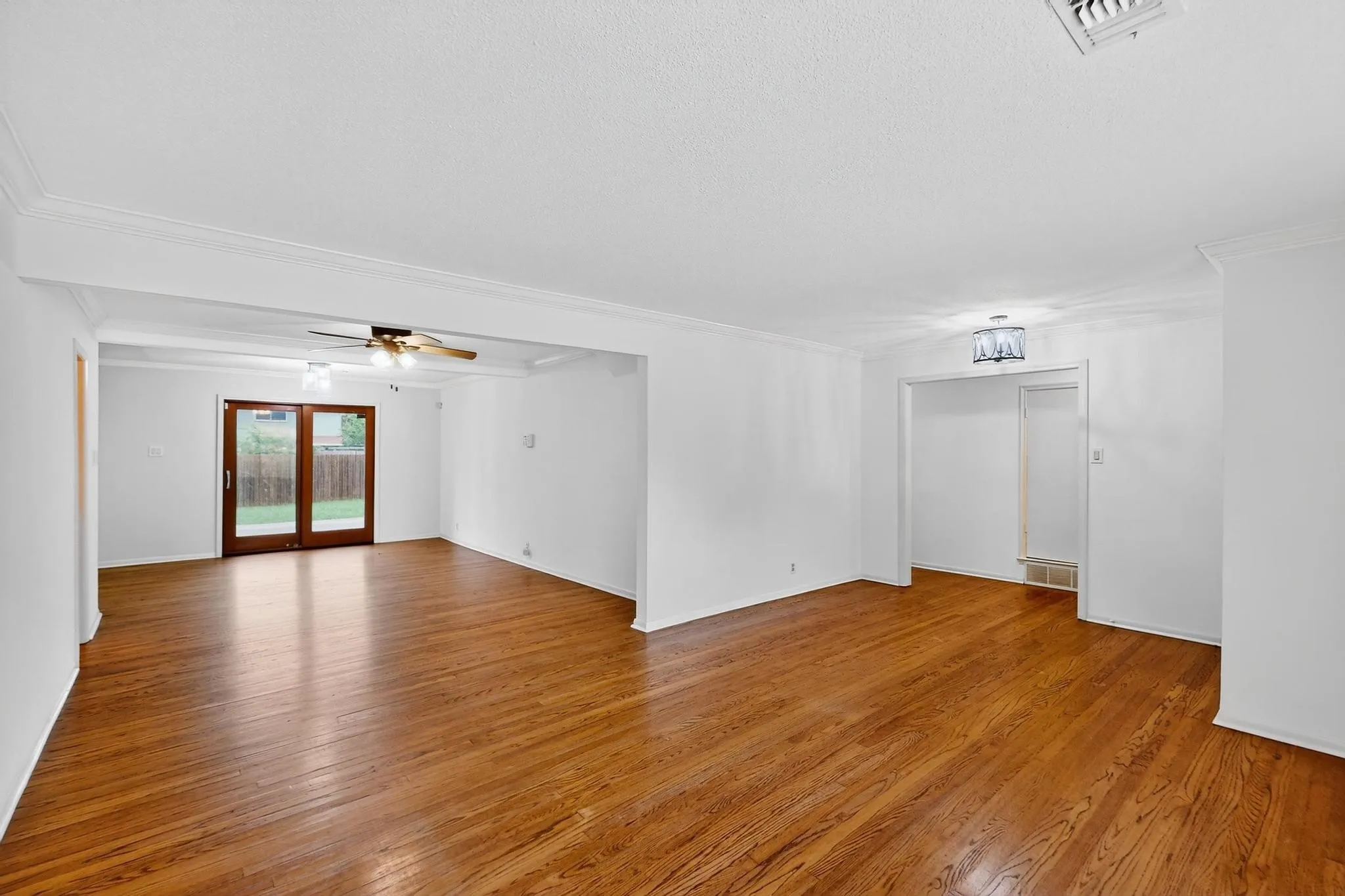 Unfurnished living room with crown molding, light wood finished floors, and ceiling fan