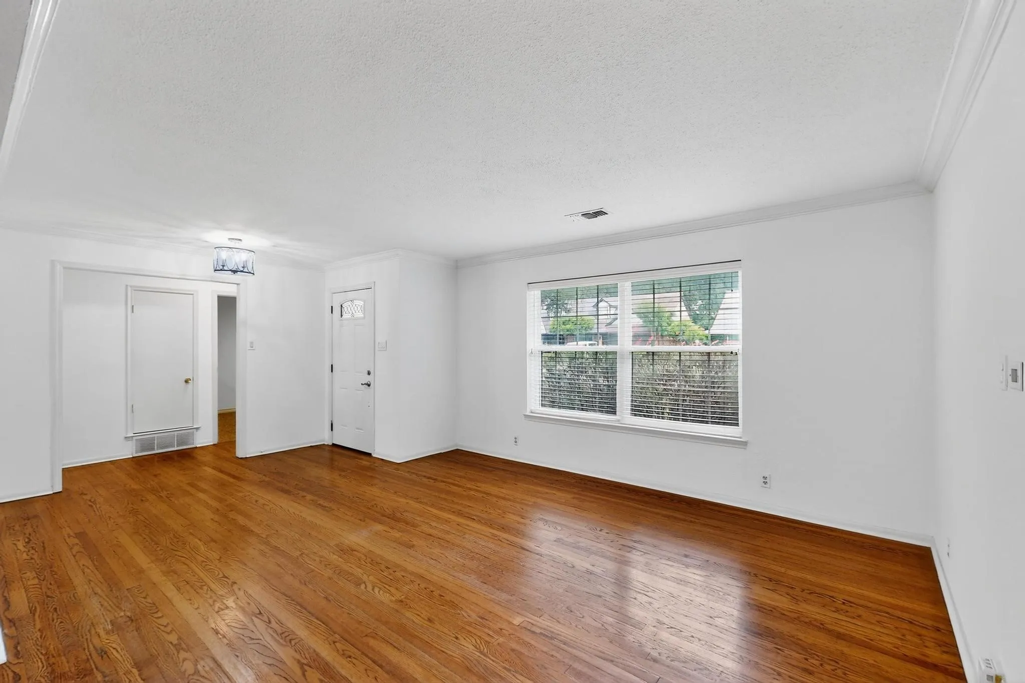 Empty room featuring a textured ceiling, wood finished floors, and ornamental molding