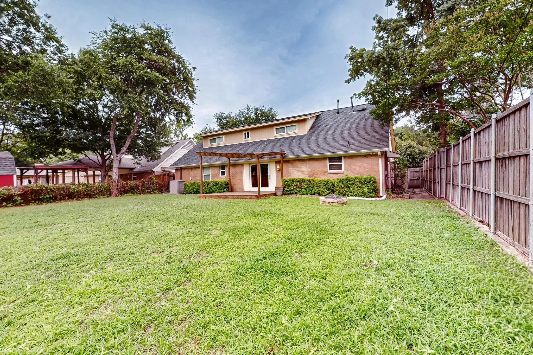 Back of property featuring a fenced backyard, a pergola, and a shingled roof