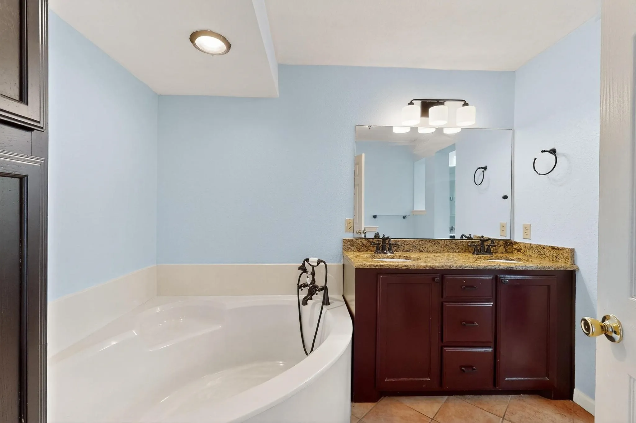 Full bath featuring tile patterned floors, a garden tub, and double vanity
