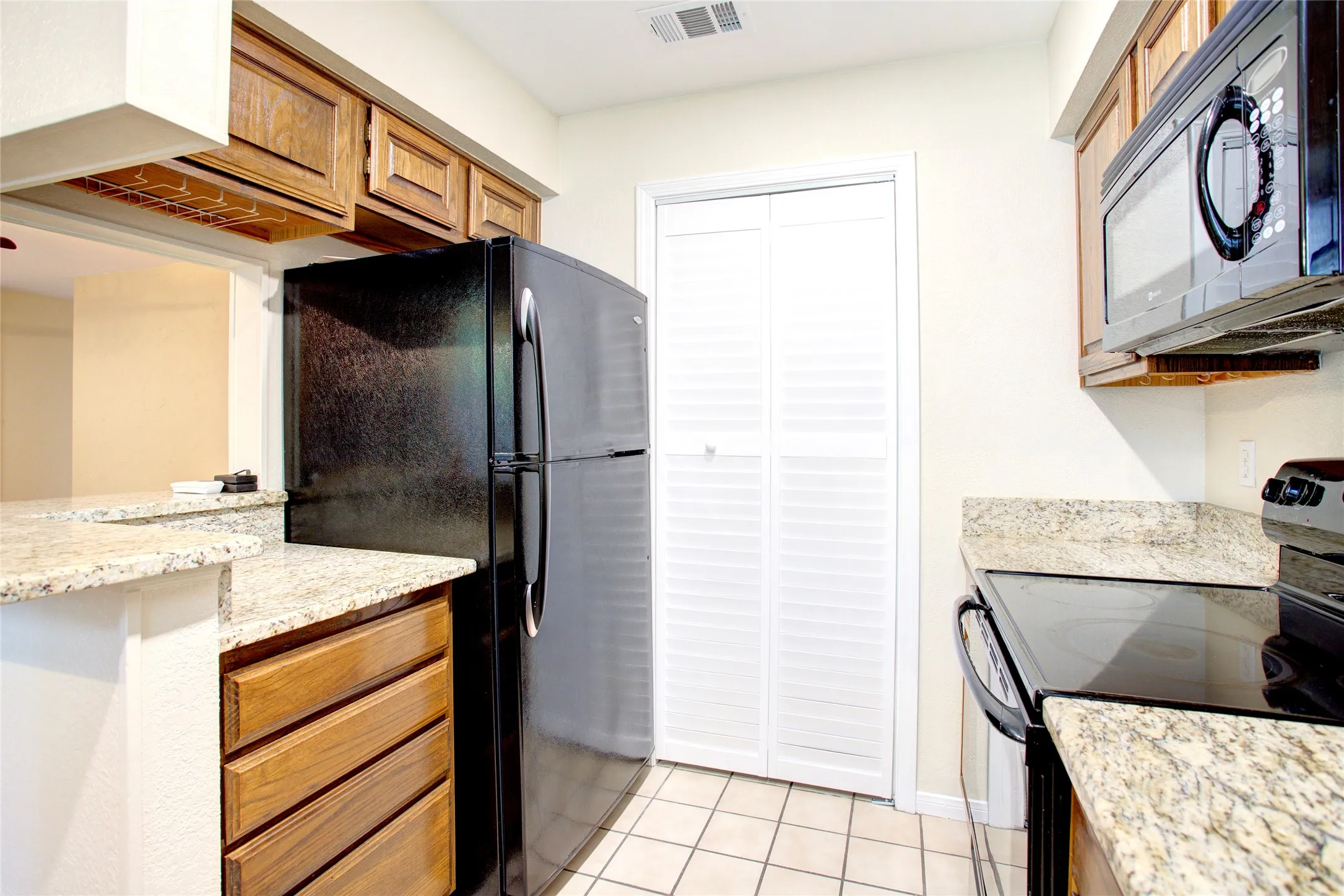 Kitchen featuring wood cabinetry, light-toned stone countertops, and tile flooring