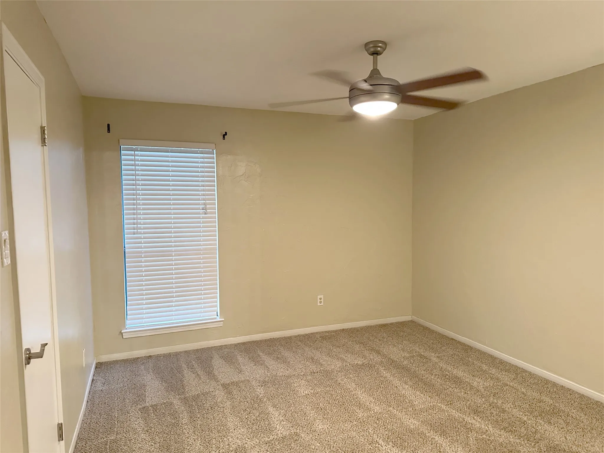 Neutral-toned carpeting, window with blinds, and a ceiling fan with integrated lighting