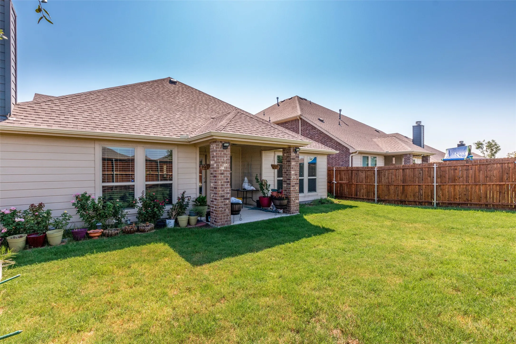 Rear view of house with a fenced backyard, a patio, and a shingled roof