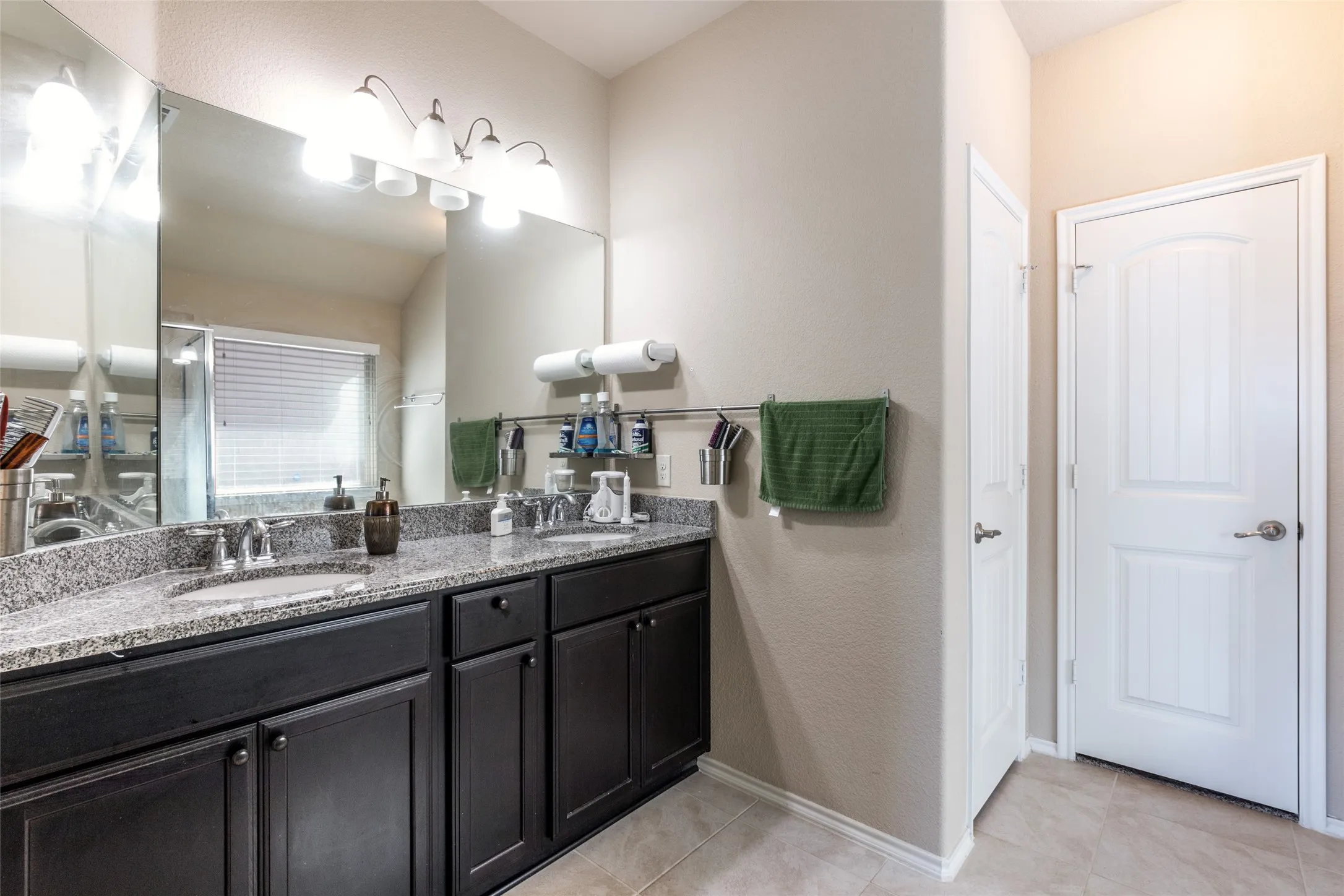 Bathroom with double vanity, tile patterned flooring, and an enclosed shower