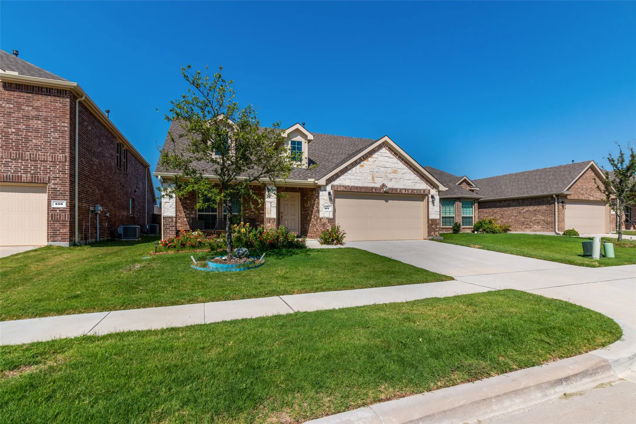 View of front of house featuring brick siding, a front lawn, driveway, and an attached garage