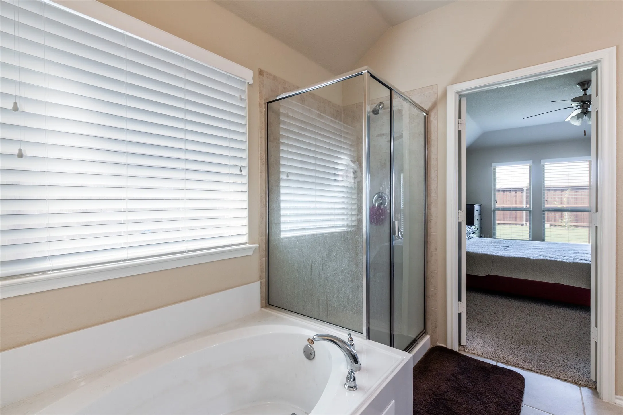 Full bath featuring connected bathroom, a bath, a shower stall, and a ceiling fan
