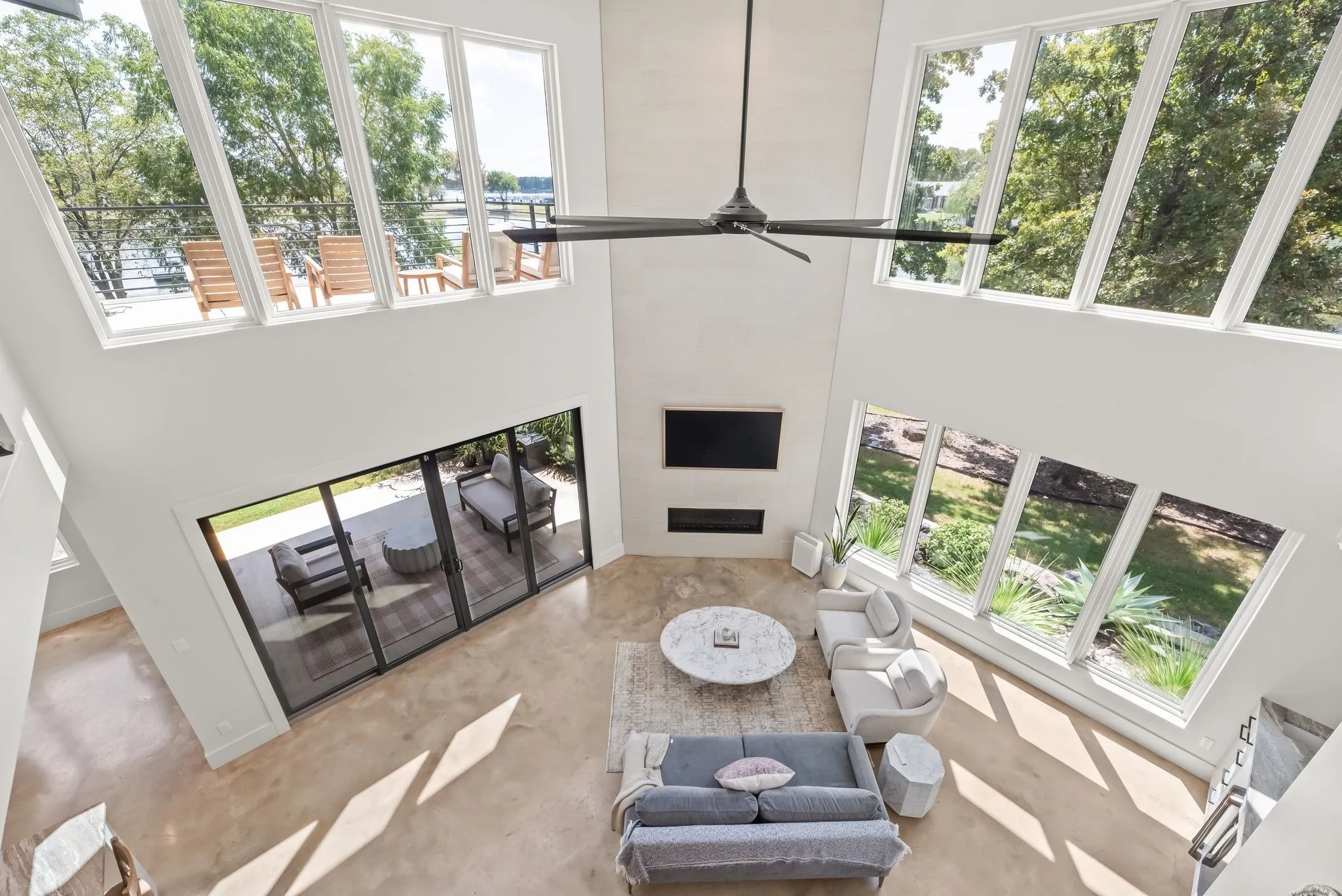 Second-floor overlook highlights the soaring cathedral ceiling, expansive windows, fireplace, and impressive open design of the living room below.