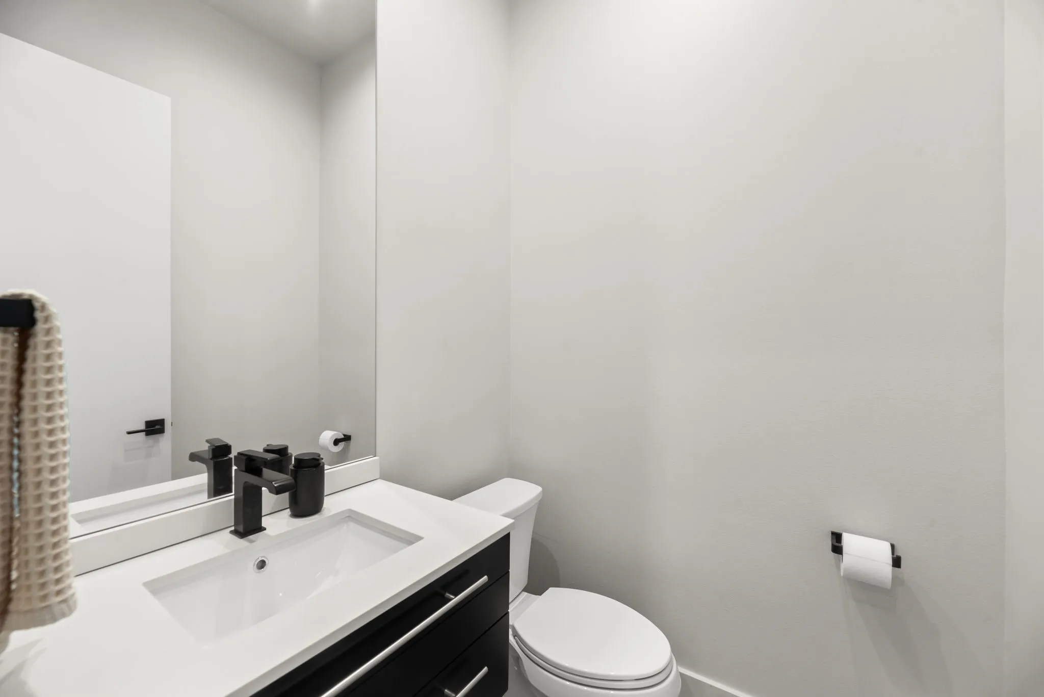 Convenient half bath features clean contemporary finishes and serves the main living and entertaining areas of the home.