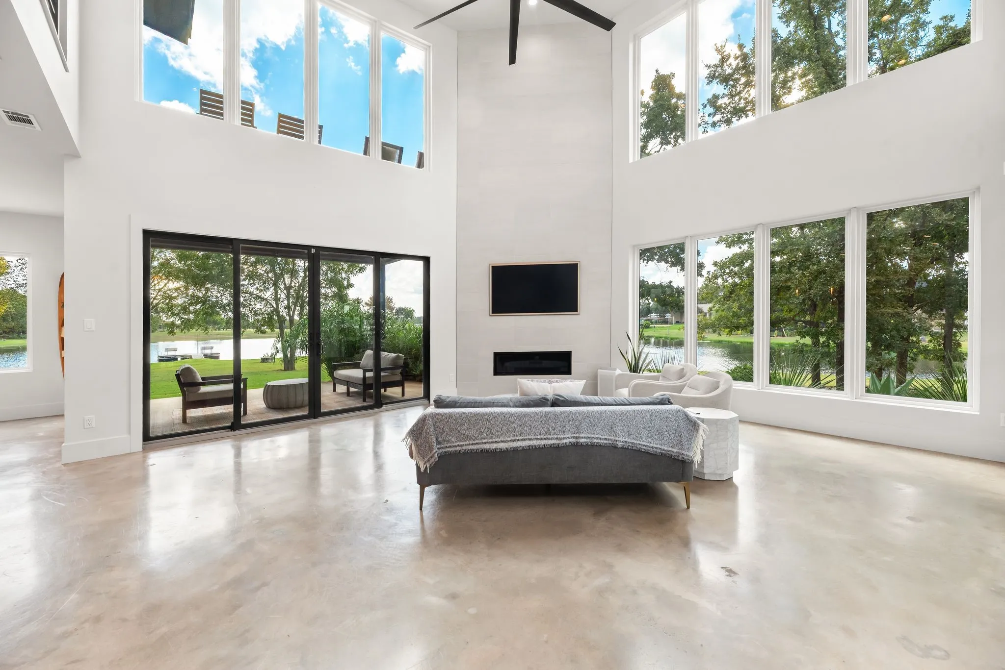 Dramatic living room features soaring cathedral ceilings, walls of windows, a fireplace, and abundant natural light in this Richland Chambers Lake home.