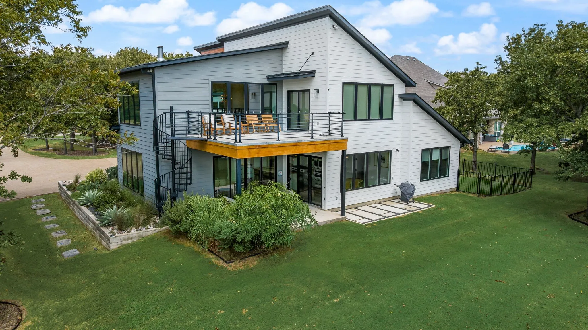 Rear exterior of 708 Clear Water Court featuring expansive windows, covered outdoor living areas, and a landscaped backyard overlooking the water.