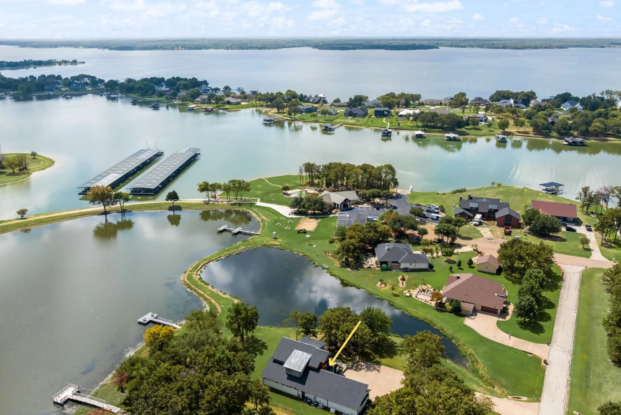 Aerial view highlights 708 Clear Water Court’s unique location in The Shores, with pond frontage just behind the home and Richland Chambers Lake, the community marina, clubhouse, and waterfront amenities nearby.