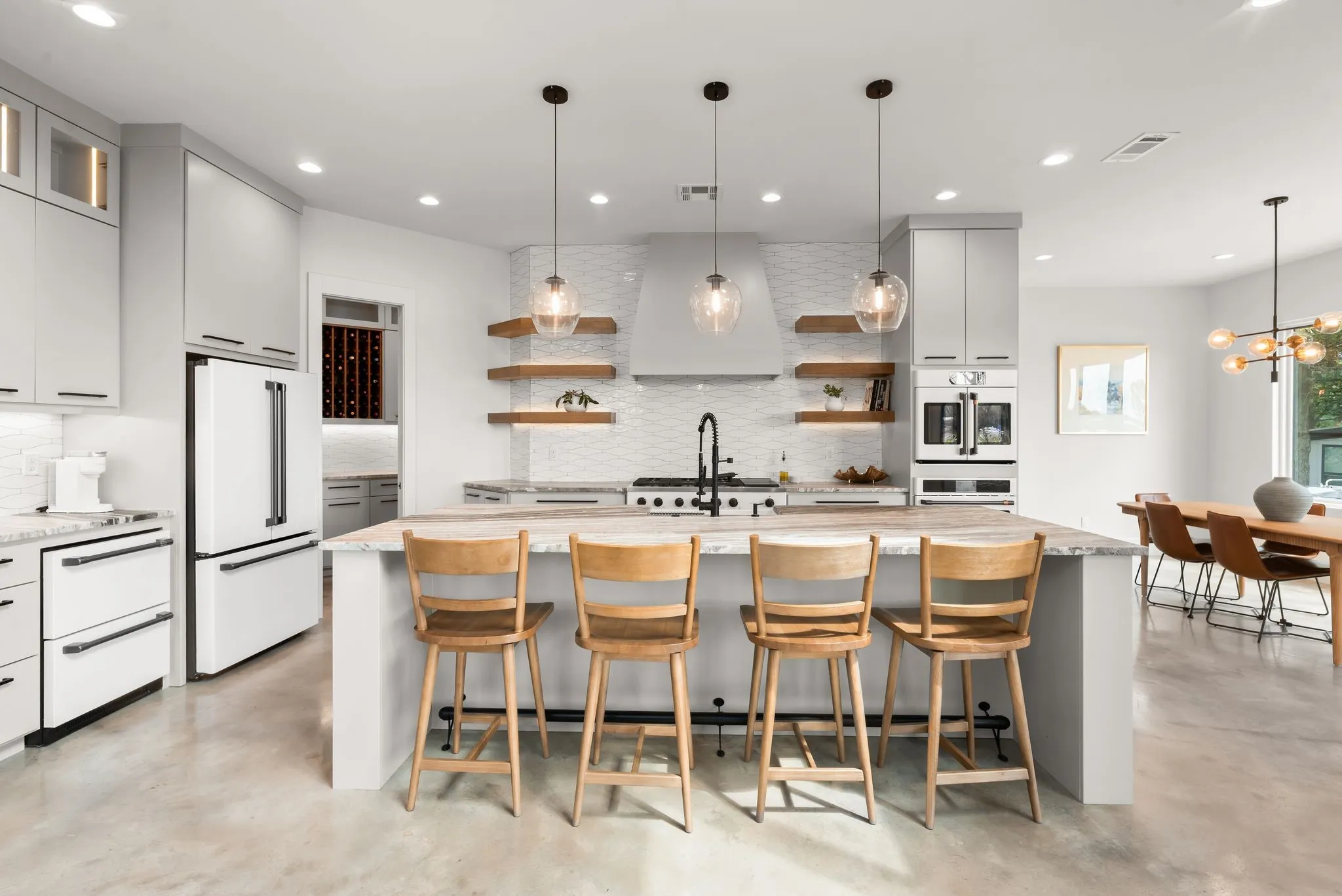 Spacious kitchen in The Shores features a large island with seating, granite countertops, custom cabinetry, gas cooktop, and designer lighting.