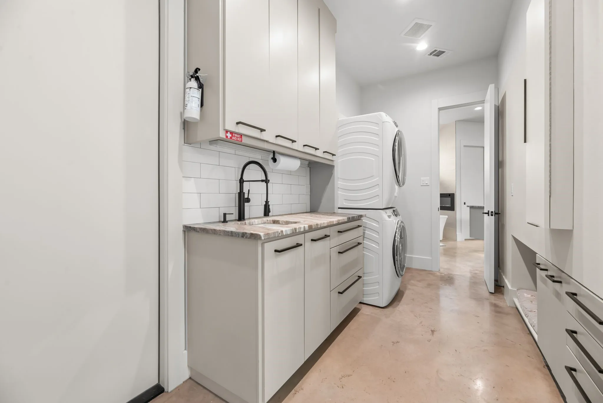 Spacious utility room offers built-in cabinetry, counter space, and full-size laundry connections for practical everyday storage and organization.