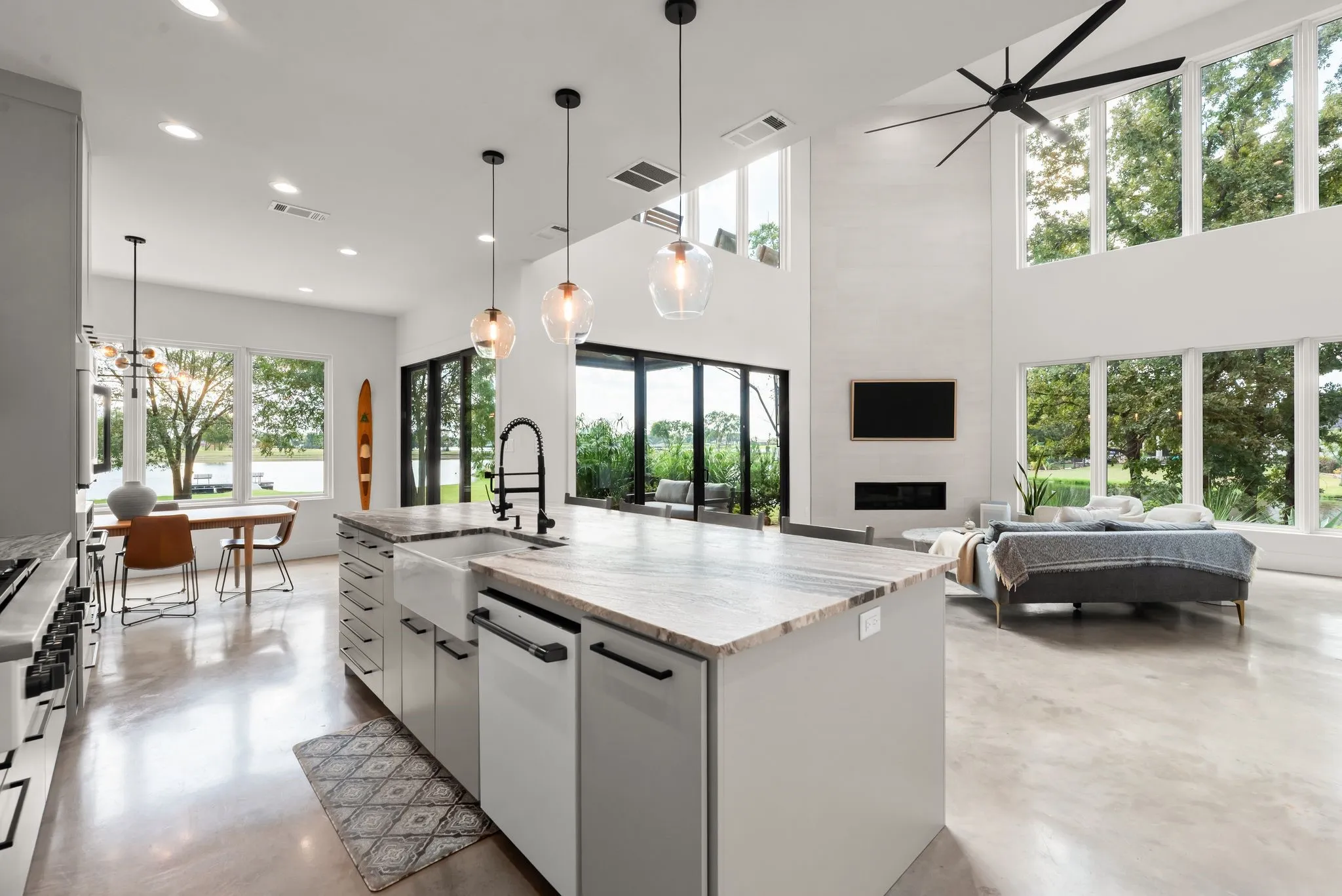 Bright open kitchen offers a large center island, abundant storage, modern finishes, and views toward the outdoor living areas and water.
