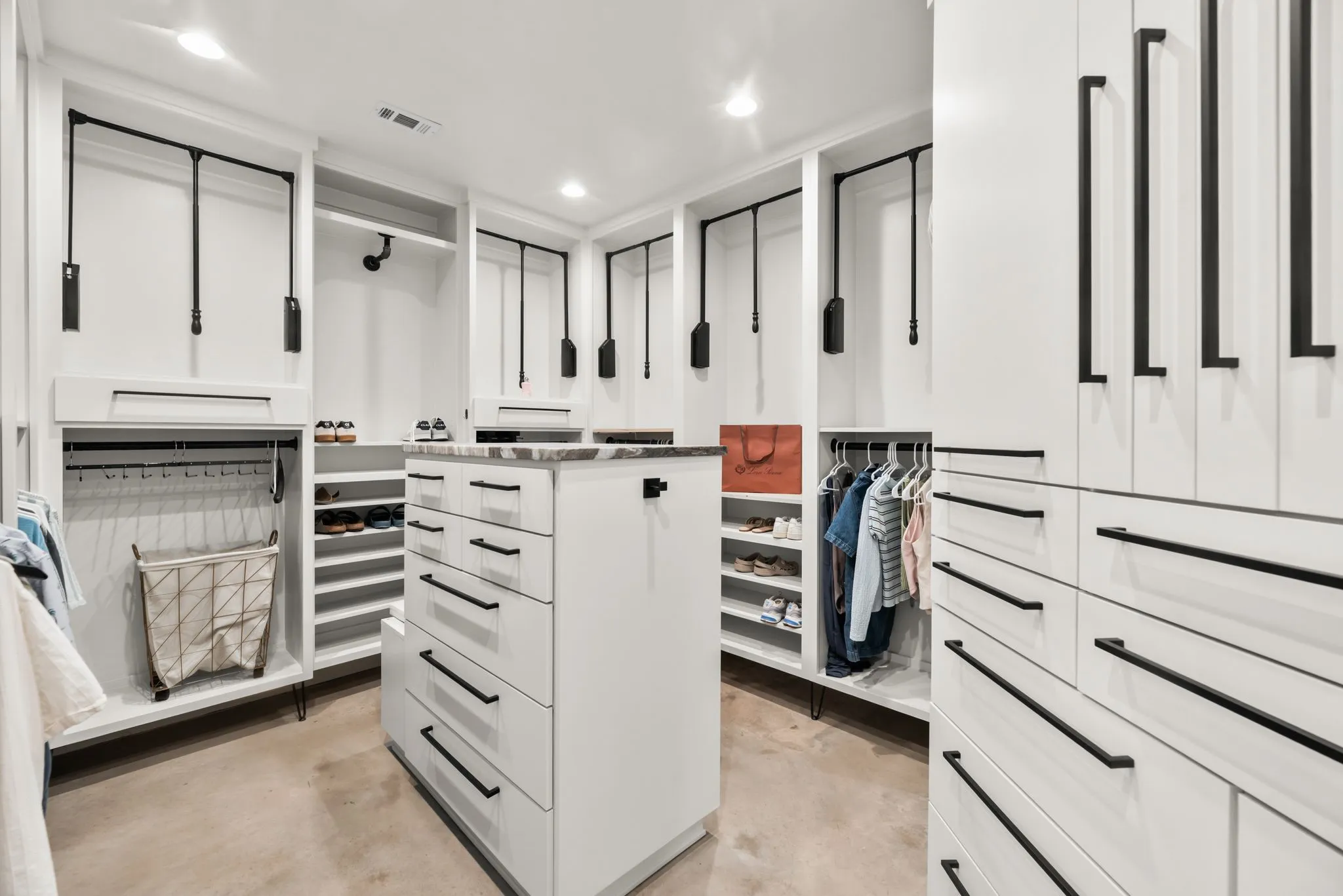 Impressive primary walk-in closet features a custom organization system with extensive built-in cabinetry, shelving, and storage.