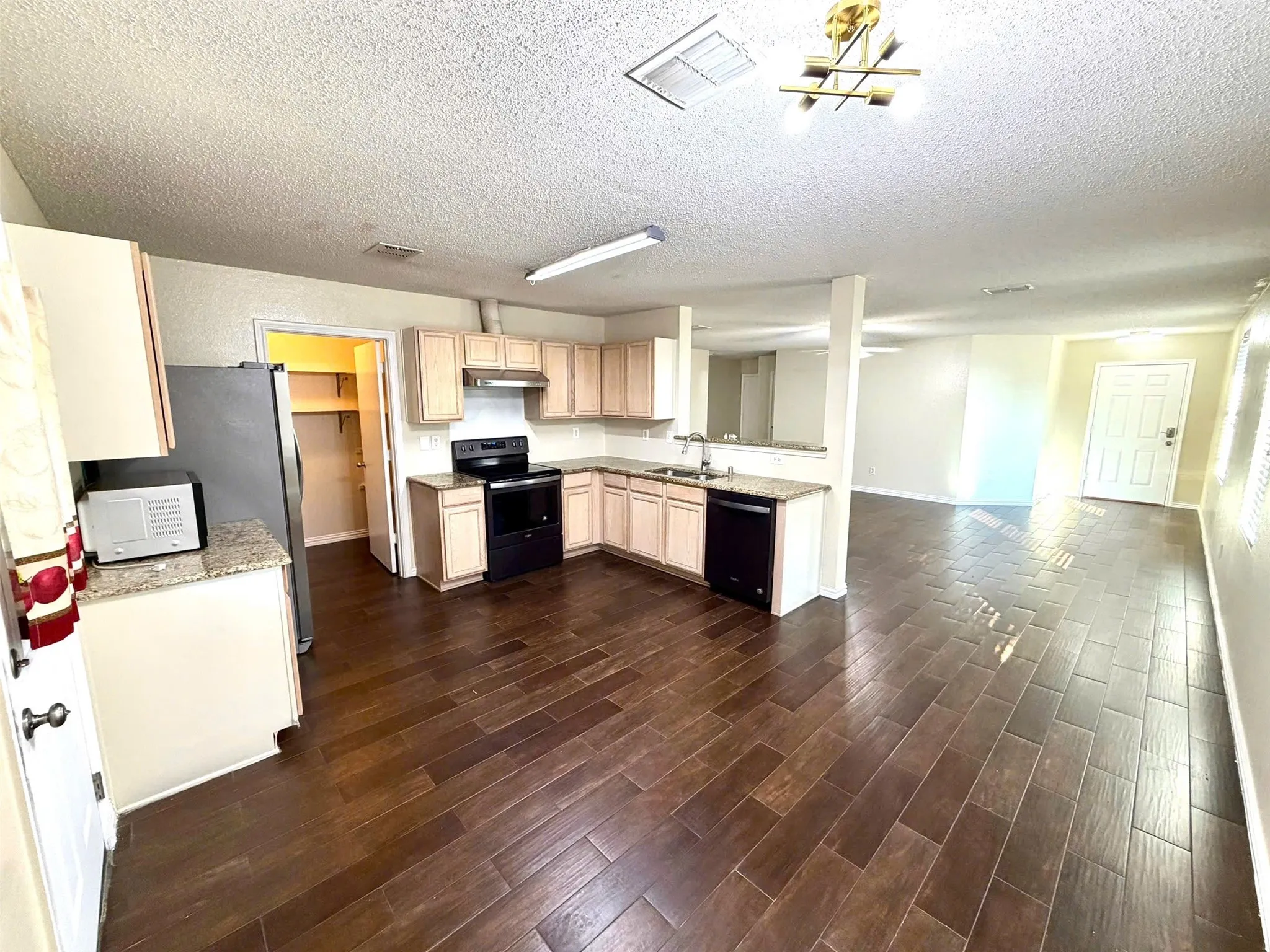 Kitchen featuring wood-finish tile flooring, light-toned cabinetry, granite-finish countertops, and a full suite of black appliances