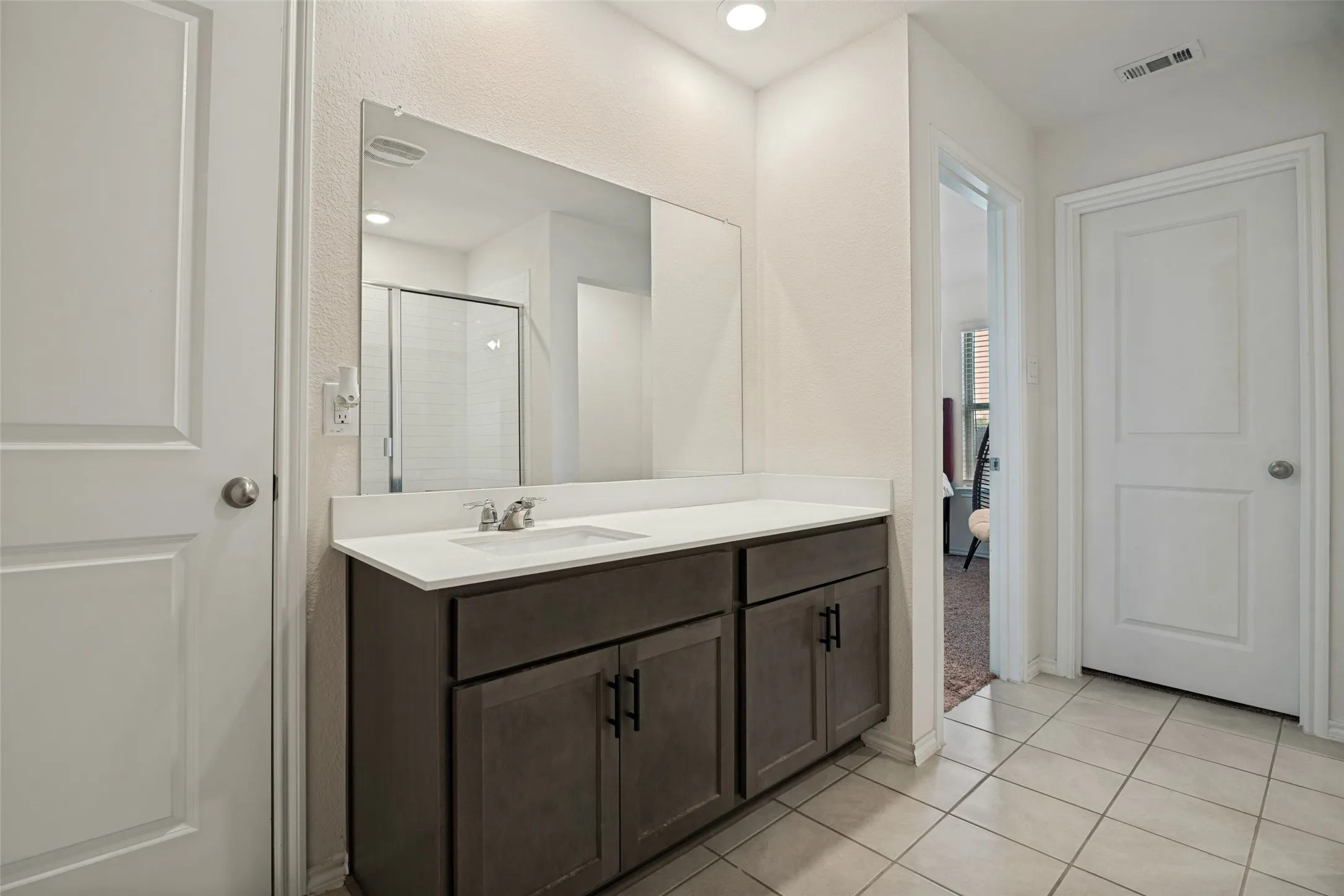 Modern vanity with a white countertop and integrated sink, complete with a large wall mirror
