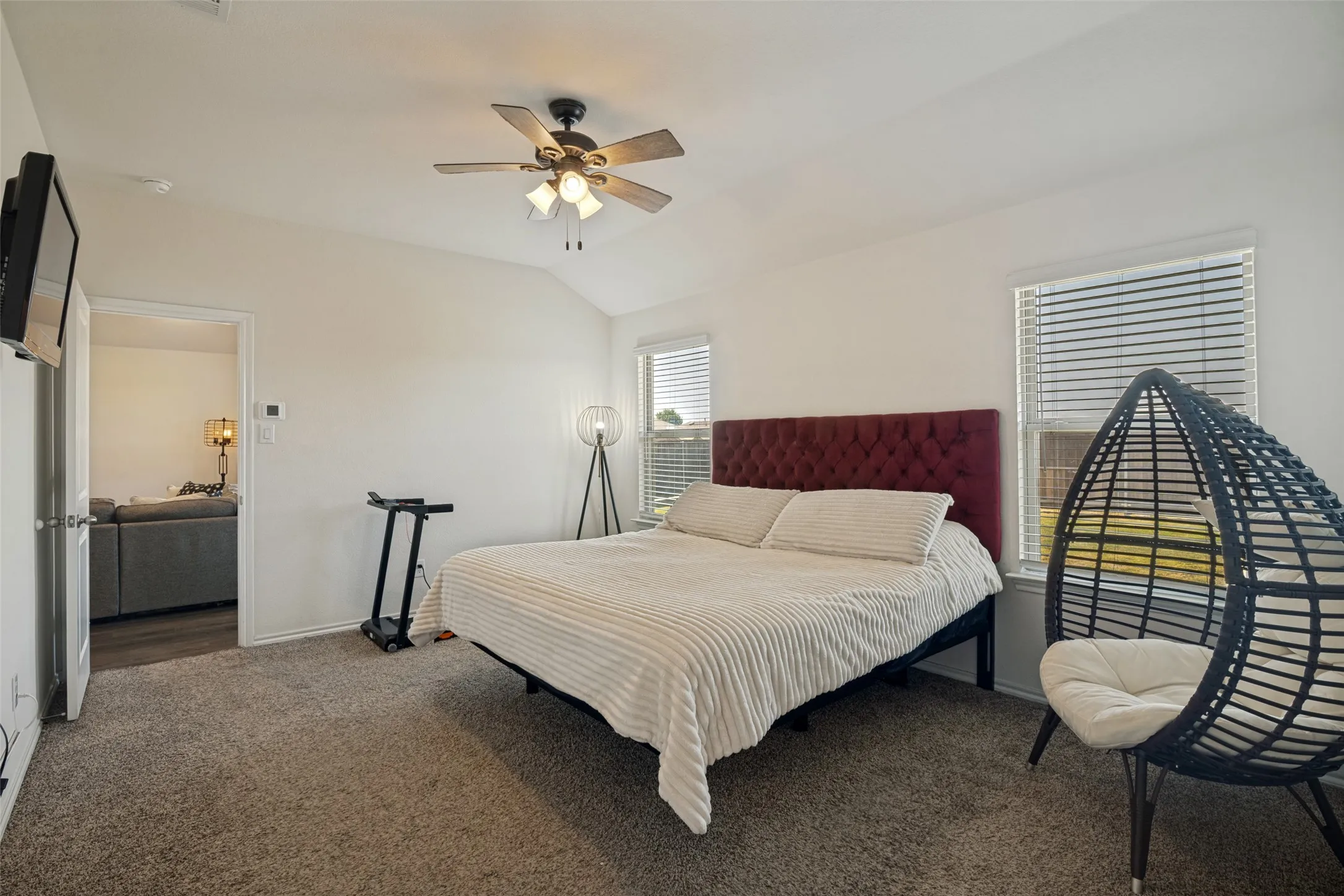 Vaulted ceiling, ceiling fan, white walls, carpet flooring, and two windows with blinds
