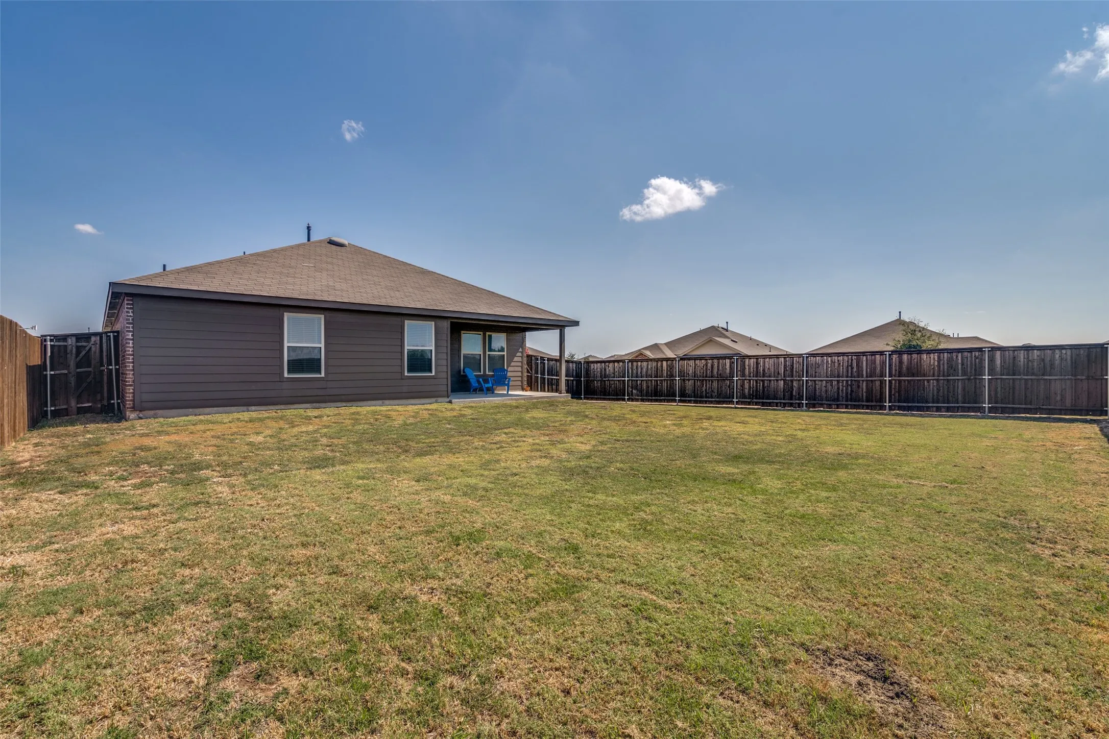 Expansive backyard featuring a privacy fence, covered patio, and a blend of siding and brick exterior