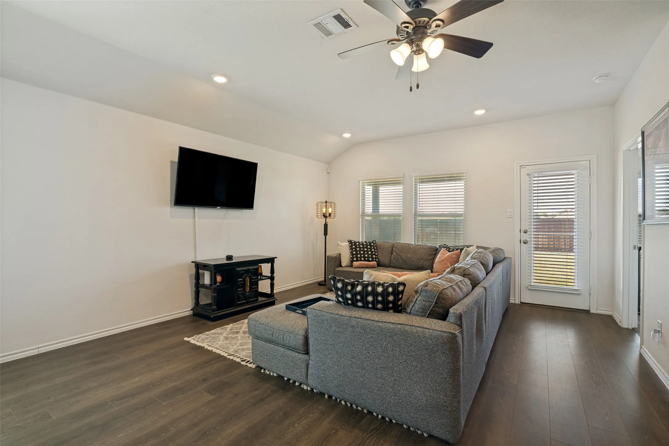 Vaulted ceiling, recessed lighting, wood-finish flooring, ceiling fan with light fixture, and door with integrated blinds