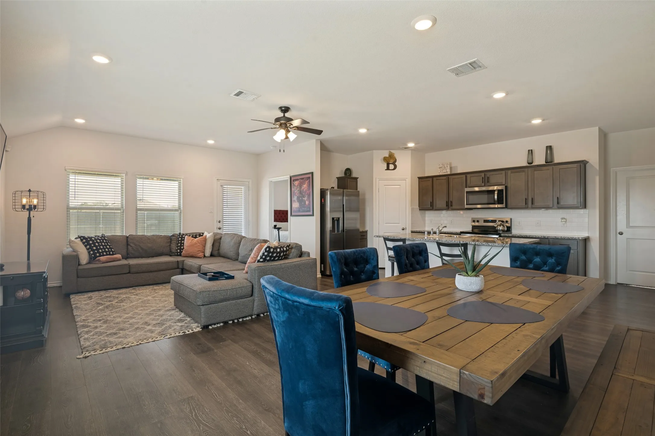 Open-concept living space featuring wood-finish flooring, recessed lighting, and a vaulted ceiling