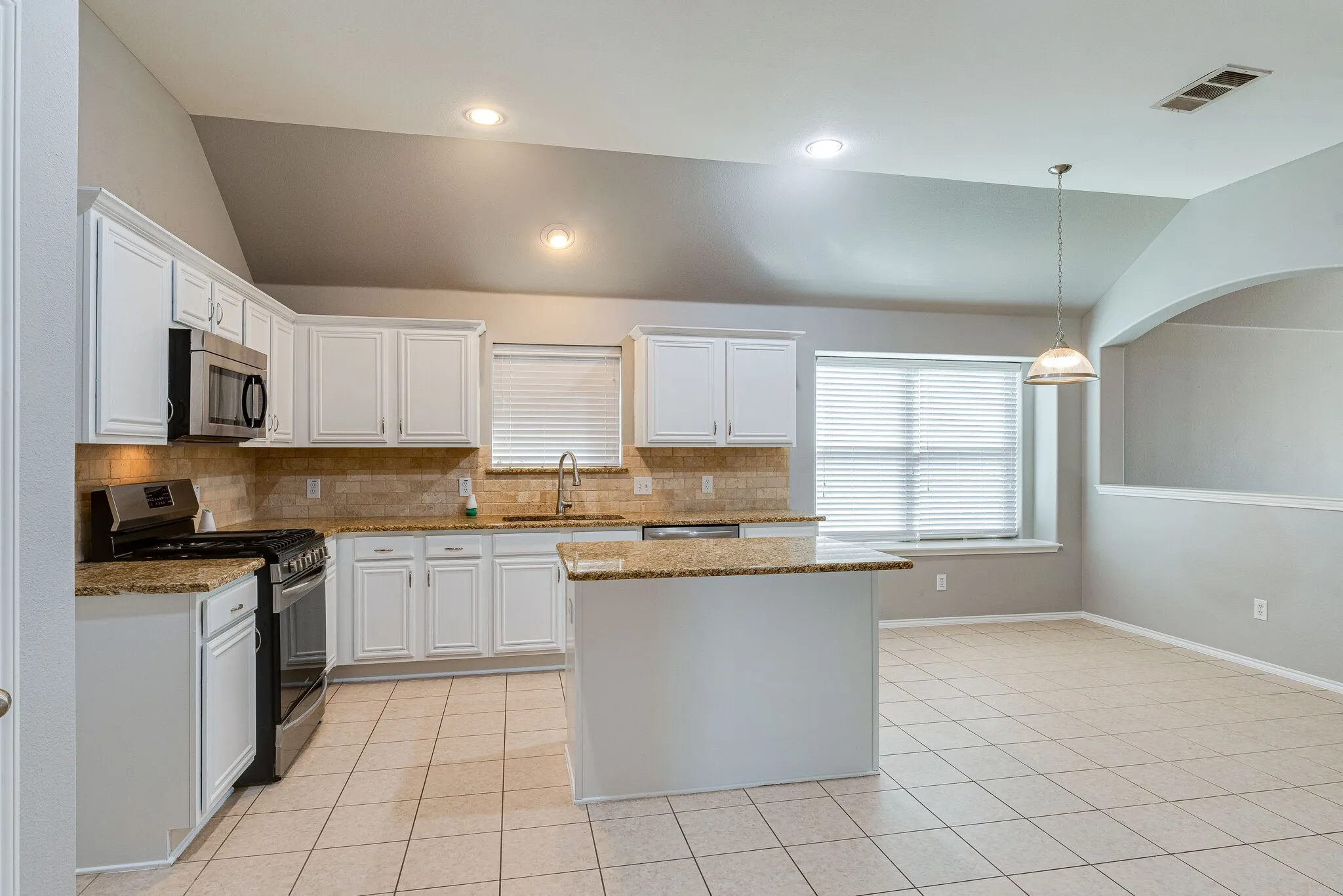 Kitchen featuring white cabinetry, granite countertops, stainless steel appliances, and tile flooring