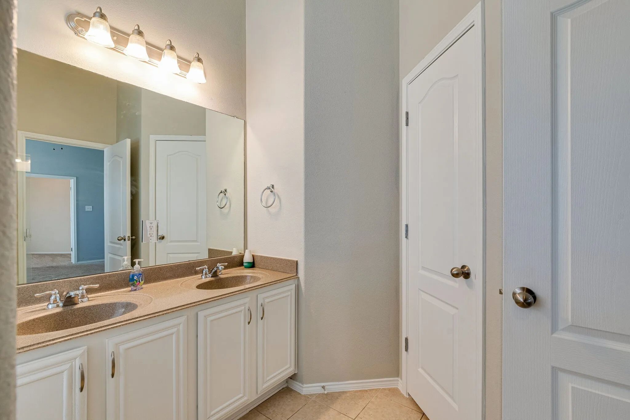Dual vanity with integrated sinks, light-toned countertop, and white cabinetry