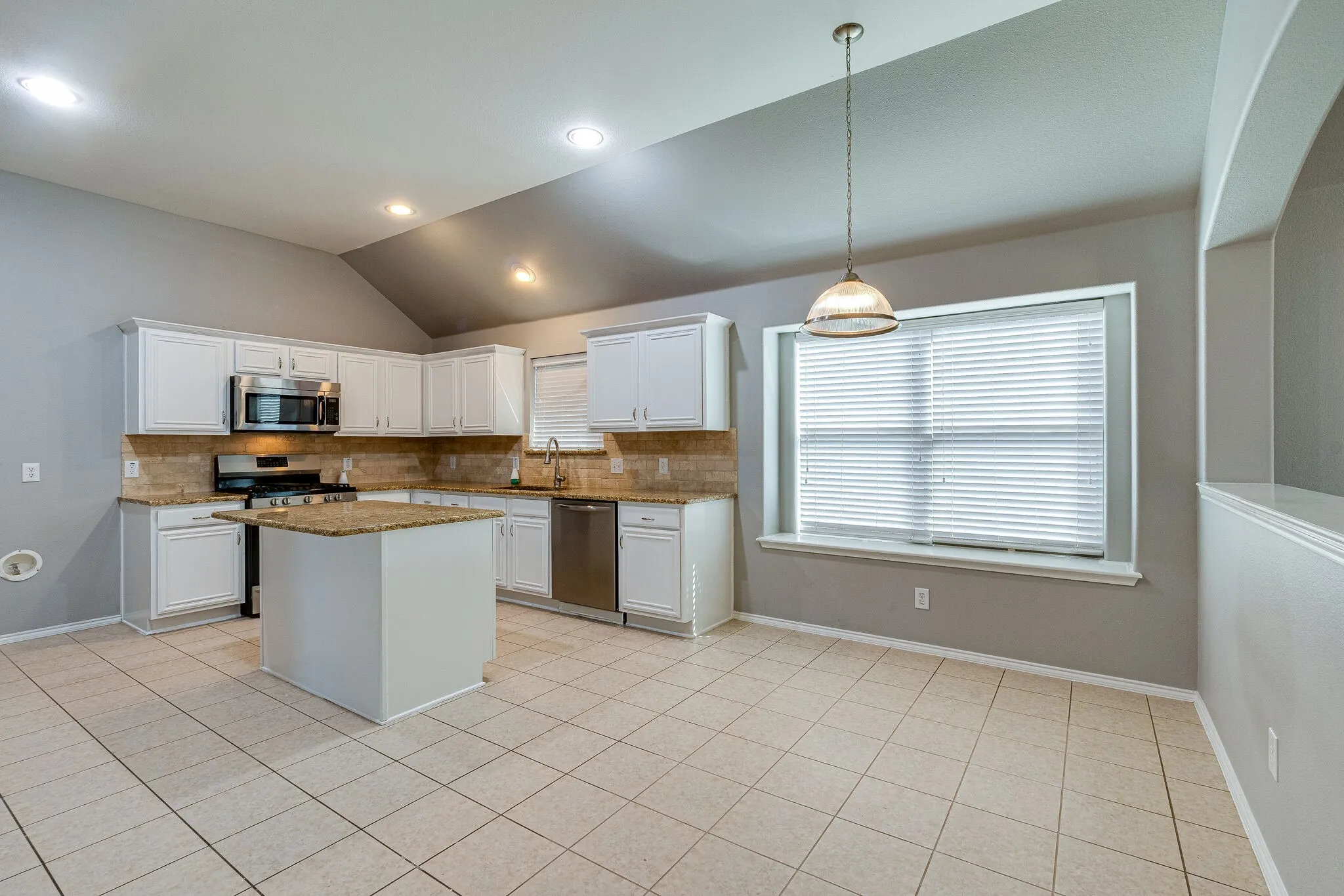 Kitchen featuring a central island, stainless steel appliances, and tile flooring