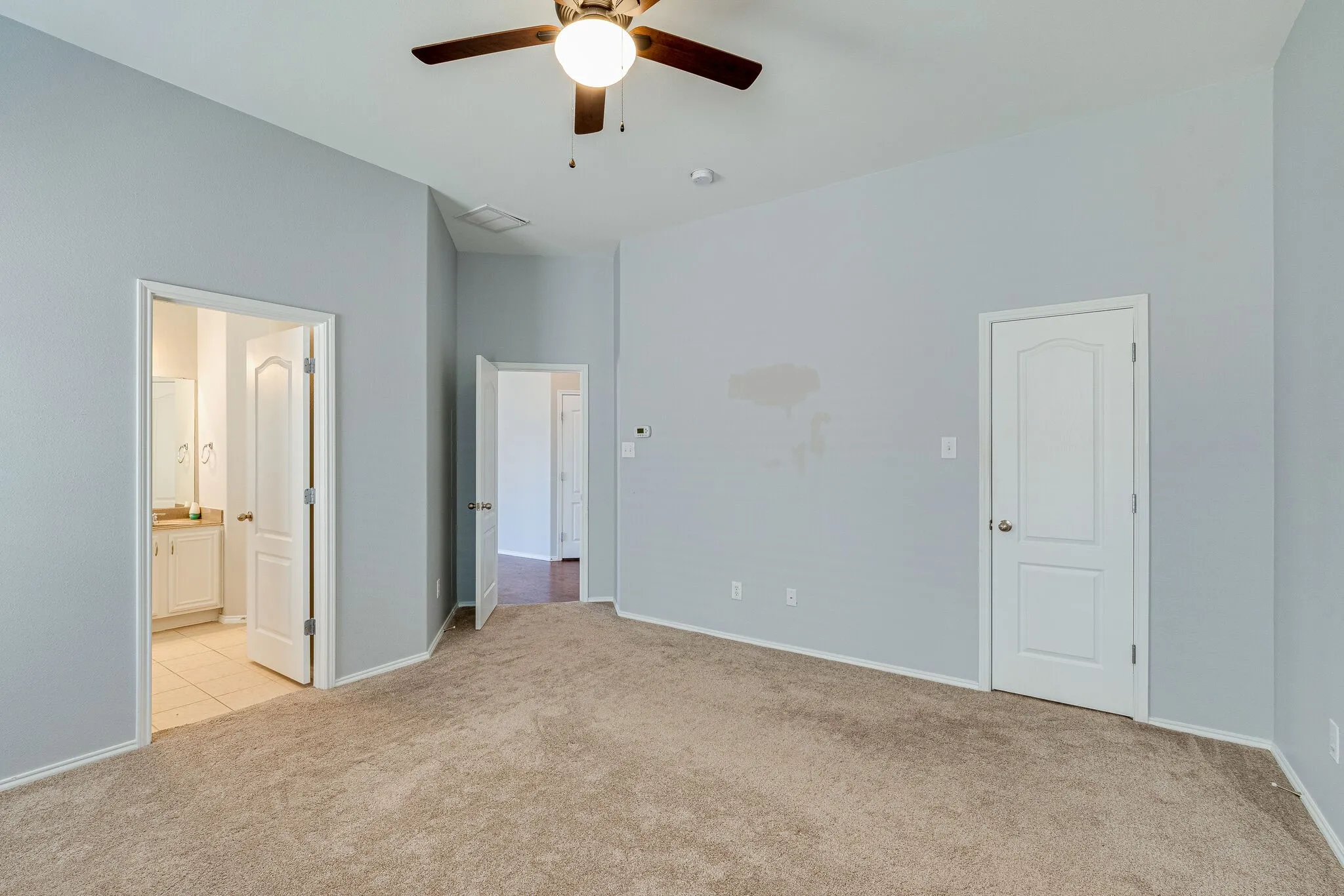 Carpeted room with a vaulted ceiling, ceiling fan, and painted walls