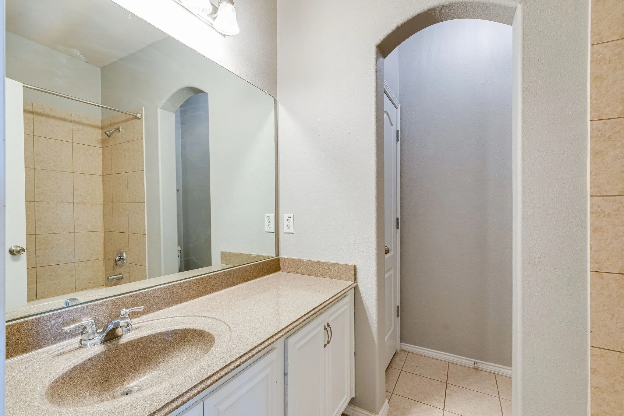Integrated vanity with a single basin sink, polished chrome faucet, and expansive wall-mounted mirror