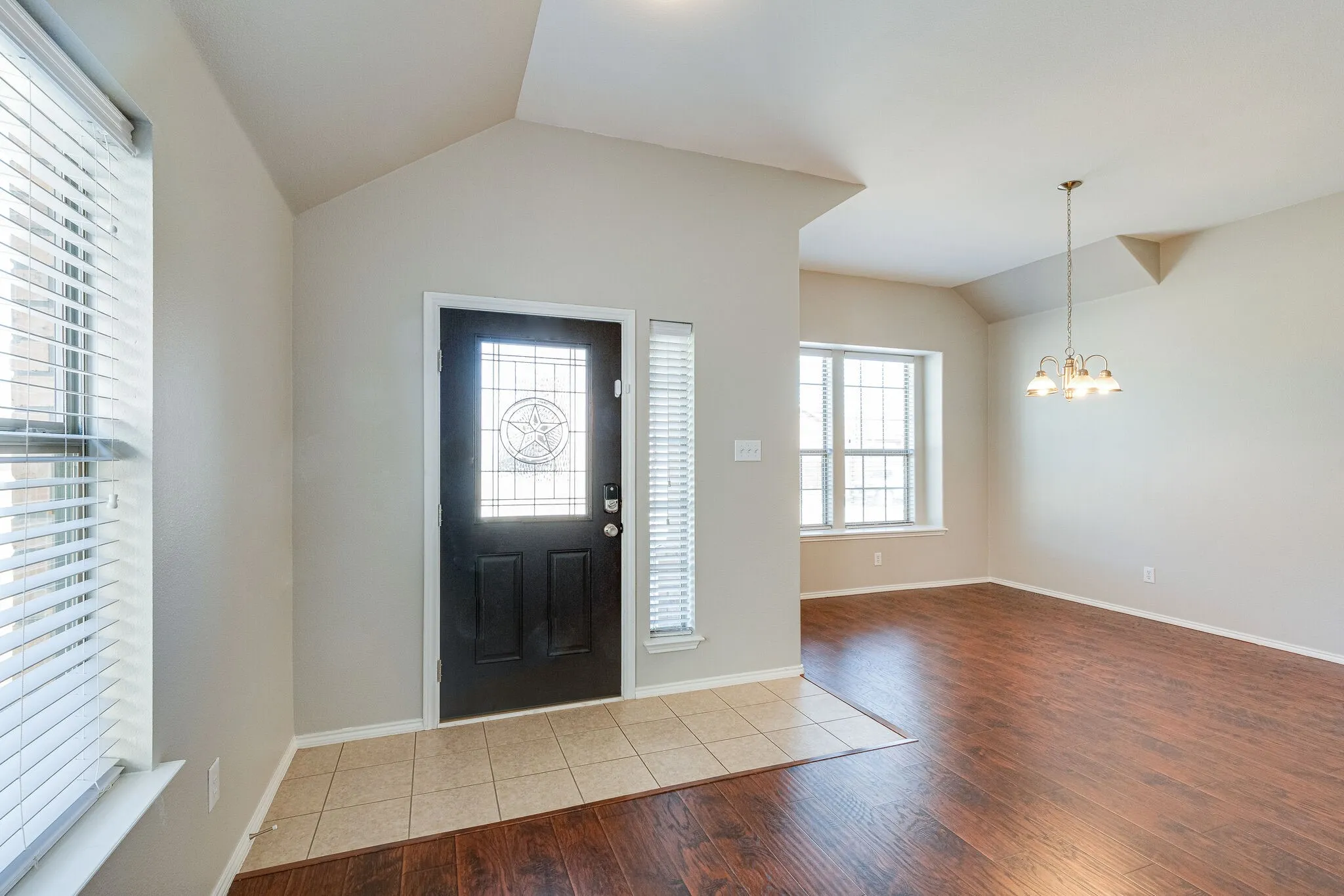 Entryway featuring a dark wood door with decorative glass, tiled flooring, and vaulted ceilings