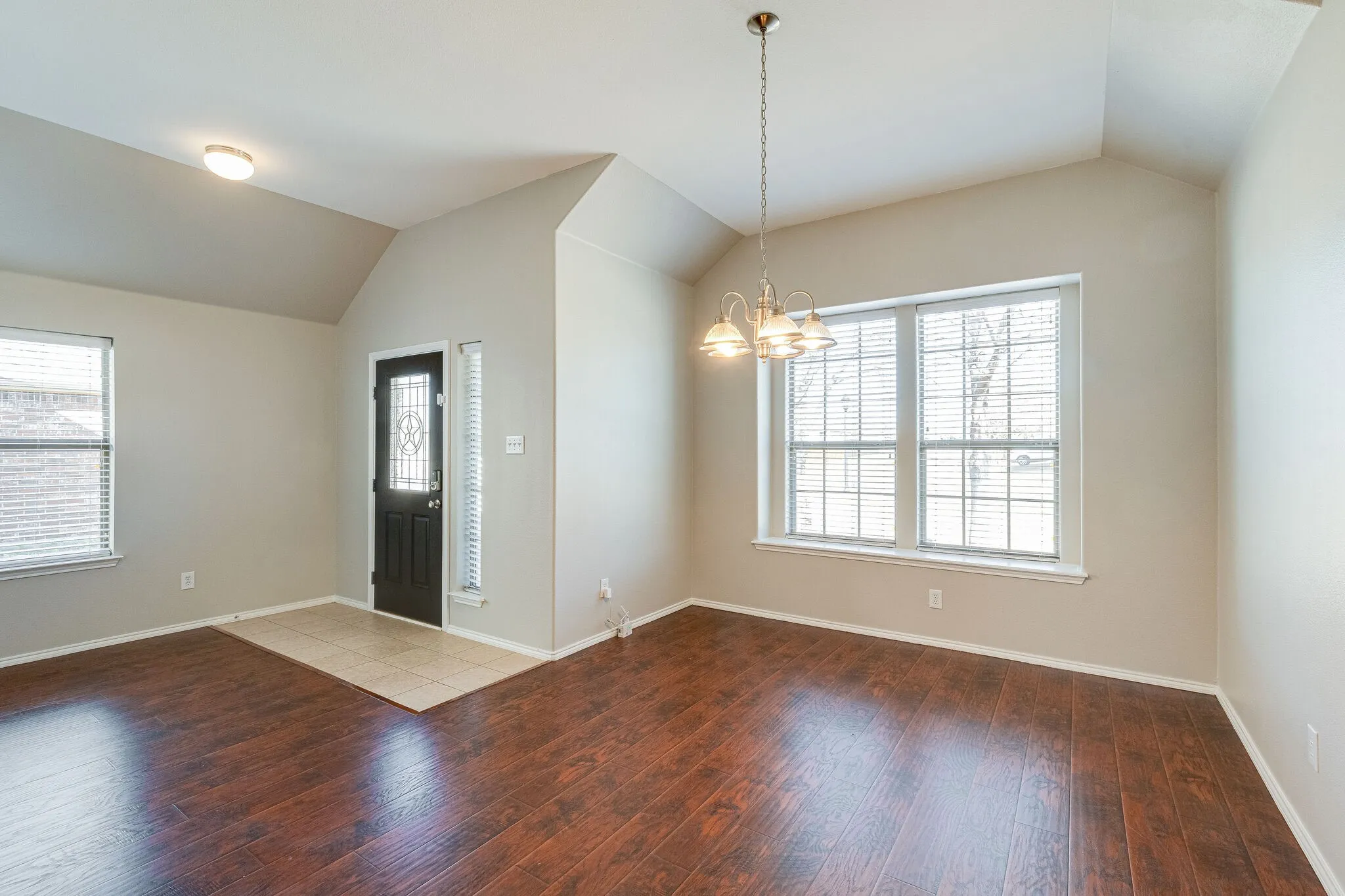 Vaulted ceilings with recessed lighting, wood-finish flooring, and a decorative front entry door with sidelight